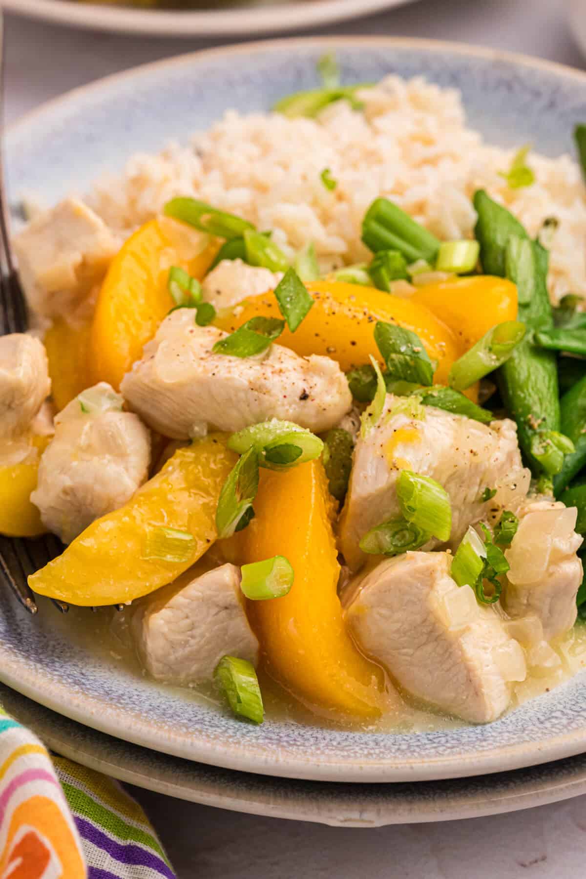 Peach chicken on a plate with rice.