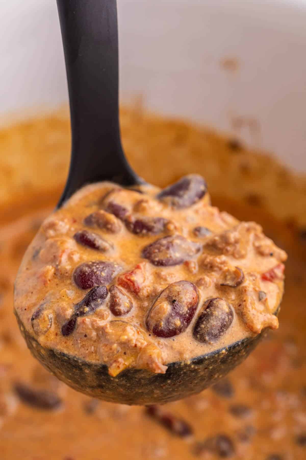 Chili cheese dip in a black ladle.