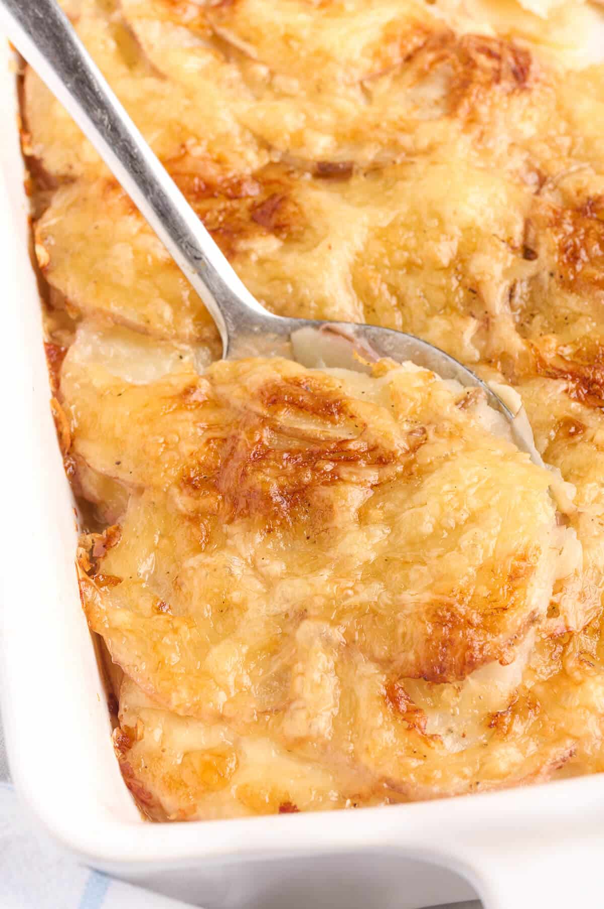 A serving spoon in a pan of Swiss Potatoes.