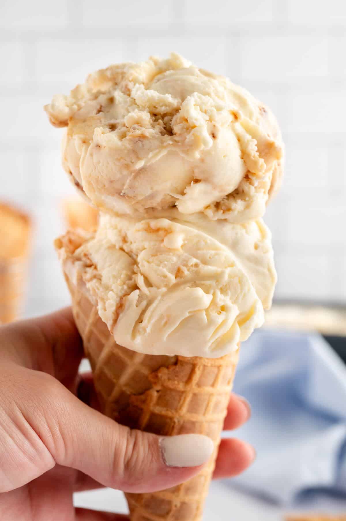A hand holding a toasted marshmallow ice cream cone.