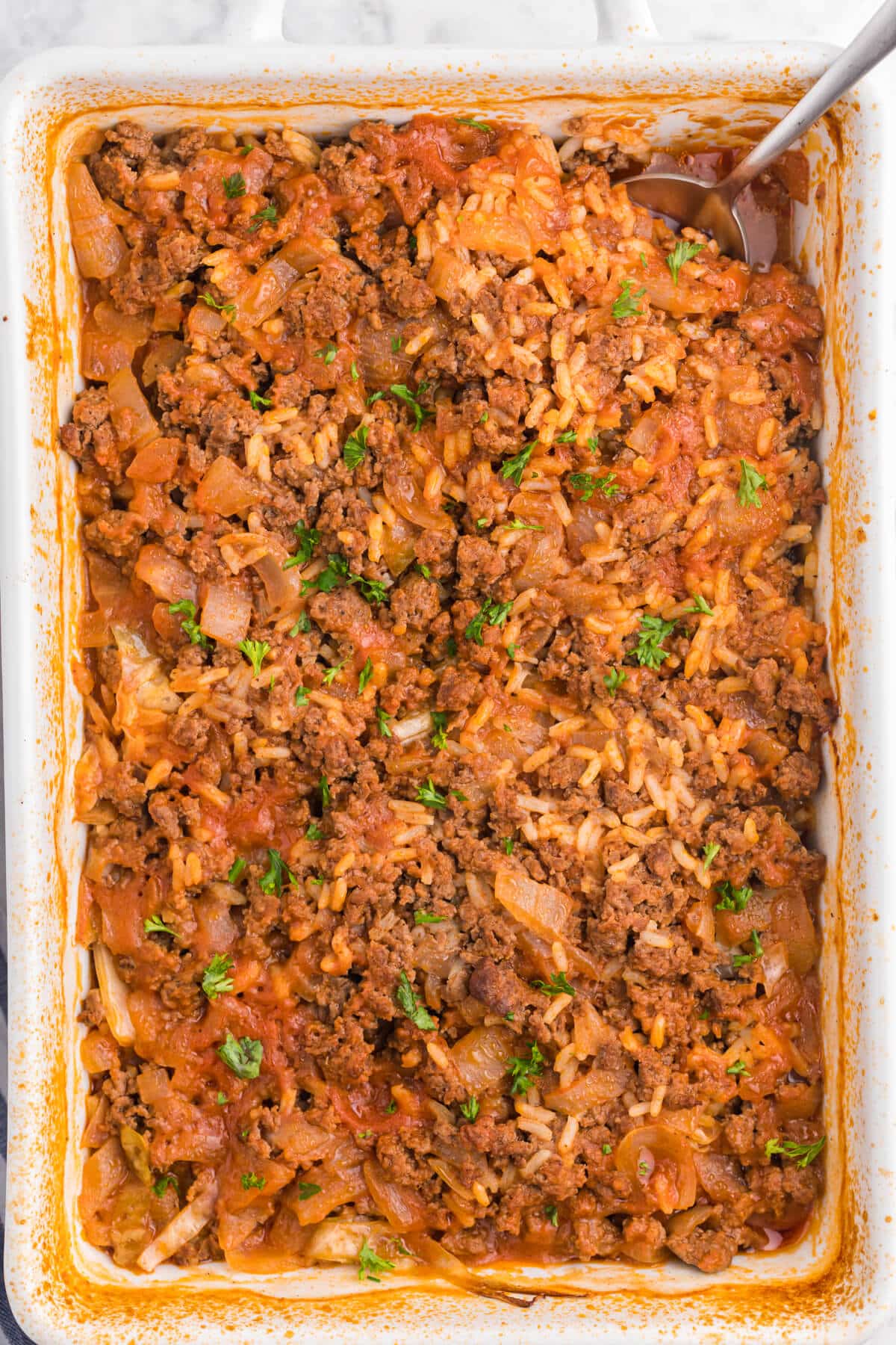 Cabbage roll casserole in a baking dish with a serving spoon.