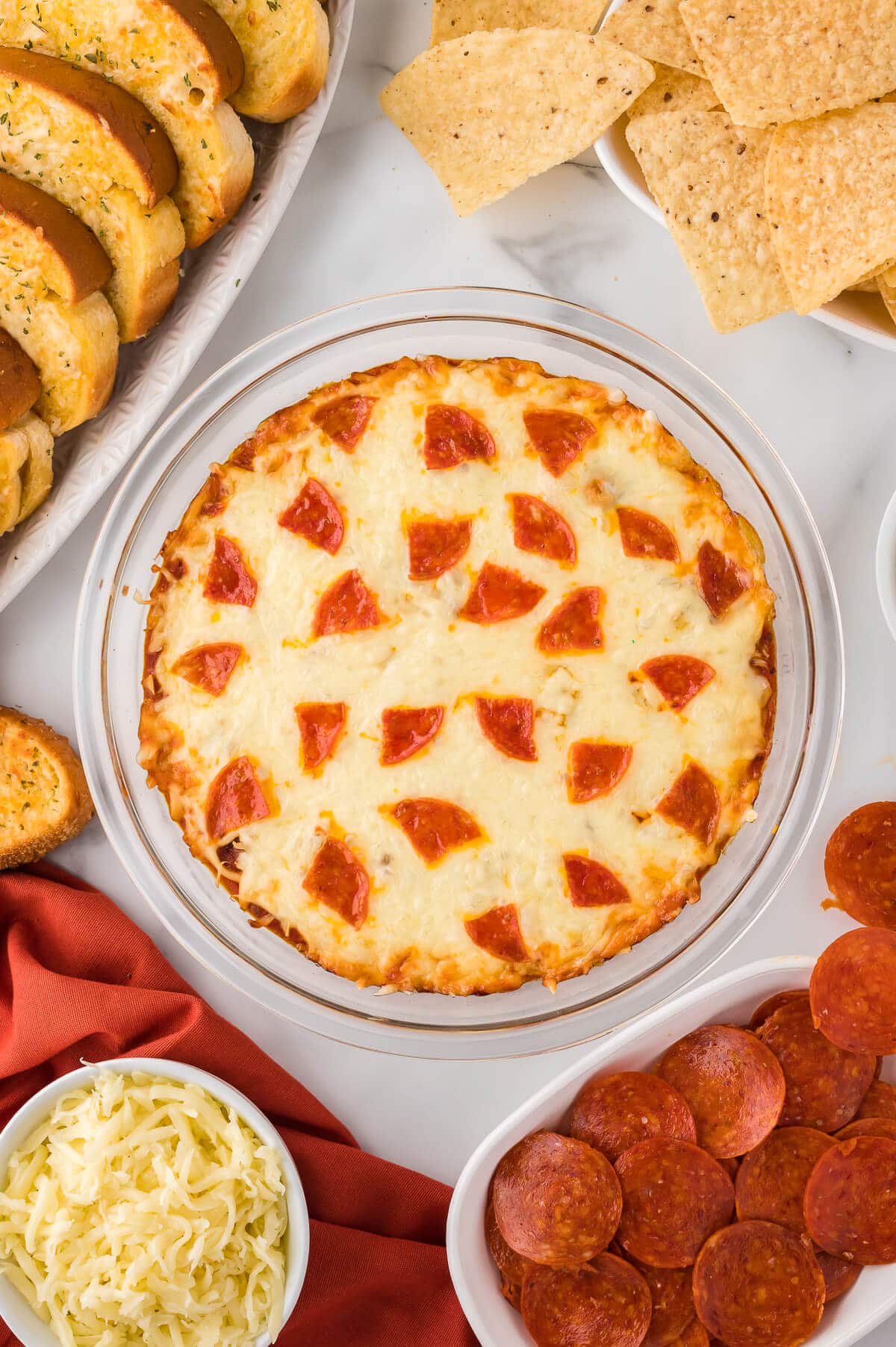 Pizza dip surrounded by ingredients.