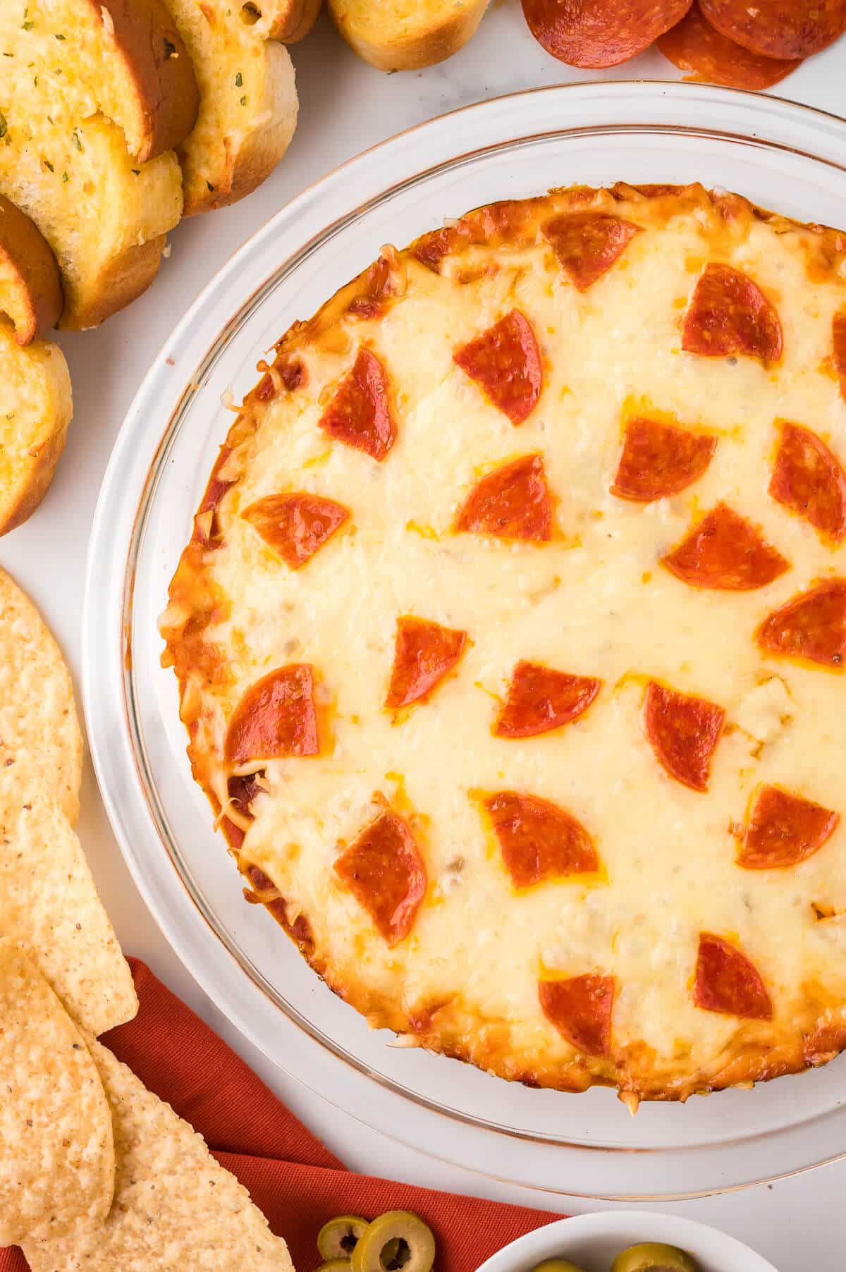 Pizza dip in a pan surrounded by garlic bread.