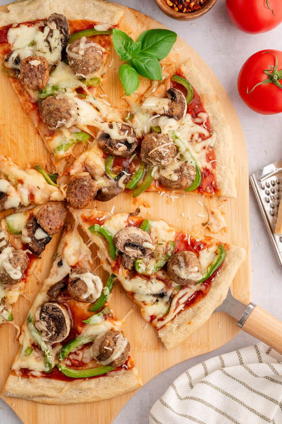 Slices of Italian meatball pizza on a wooden cutting board.