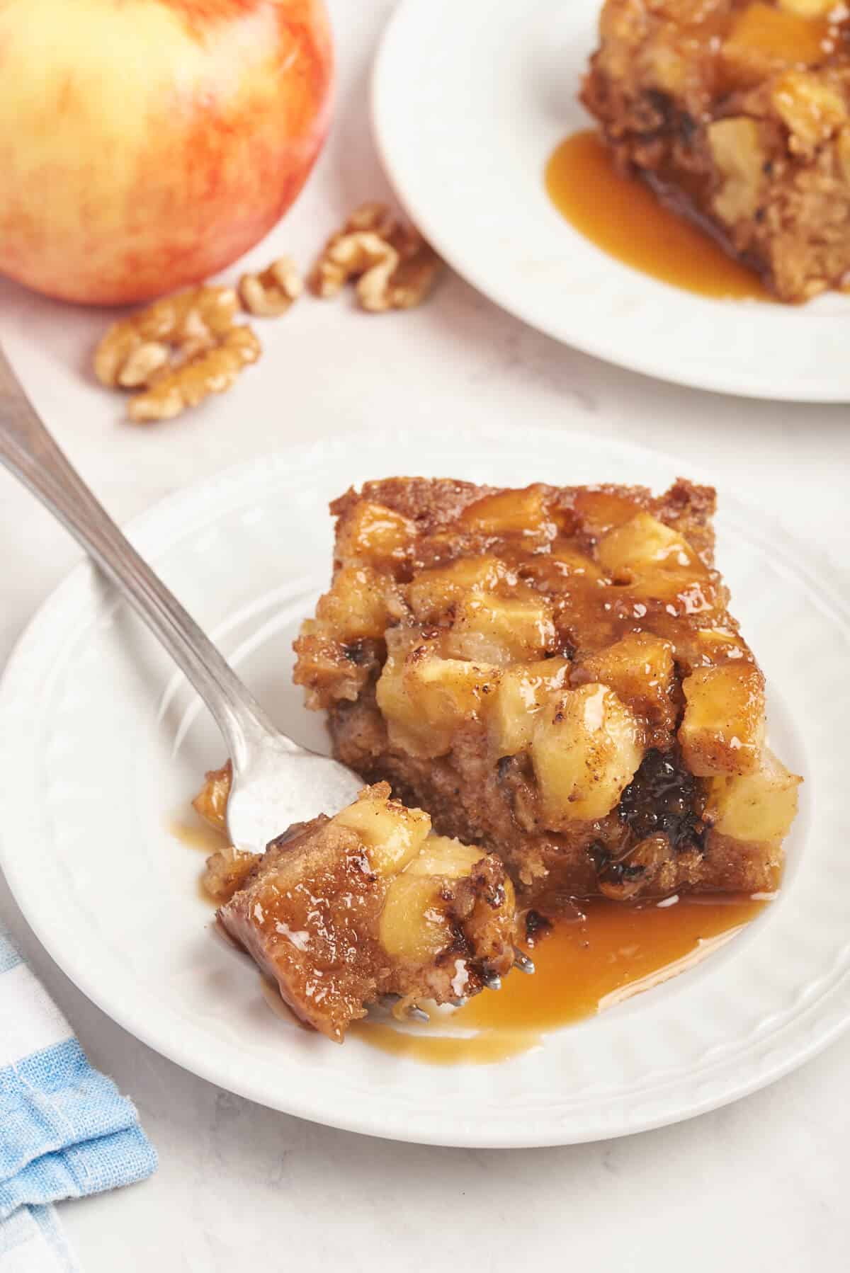 A piece of Nobby apple cake on a plate with a fork.