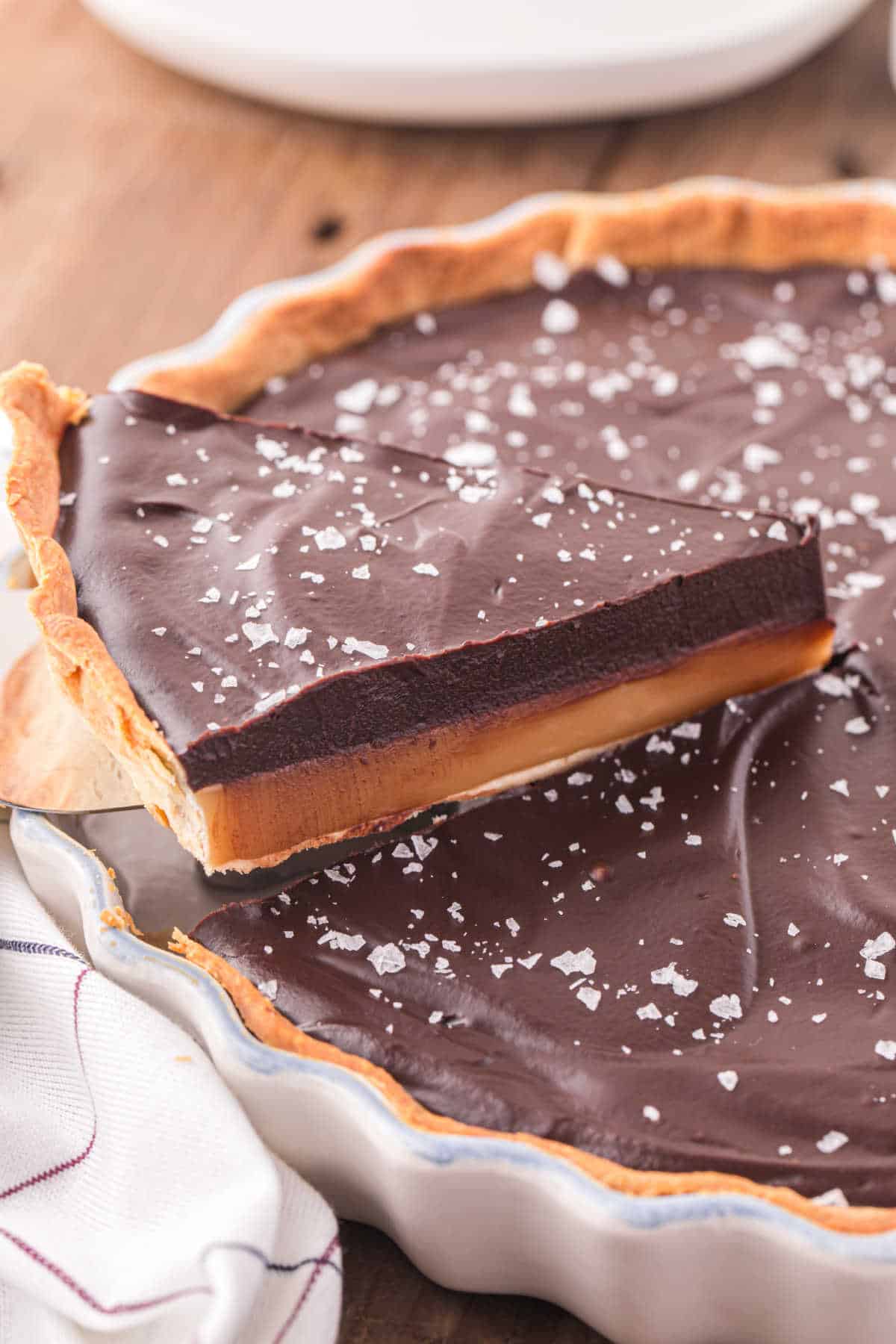 A slice of chocolate caramel tart on a spatula.