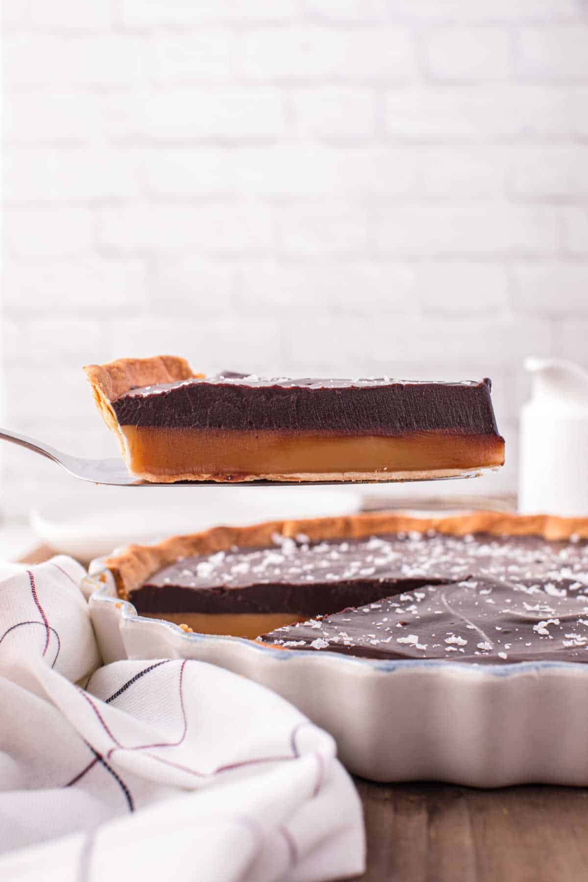 A slice of chocolate caramel tart on a spatula.