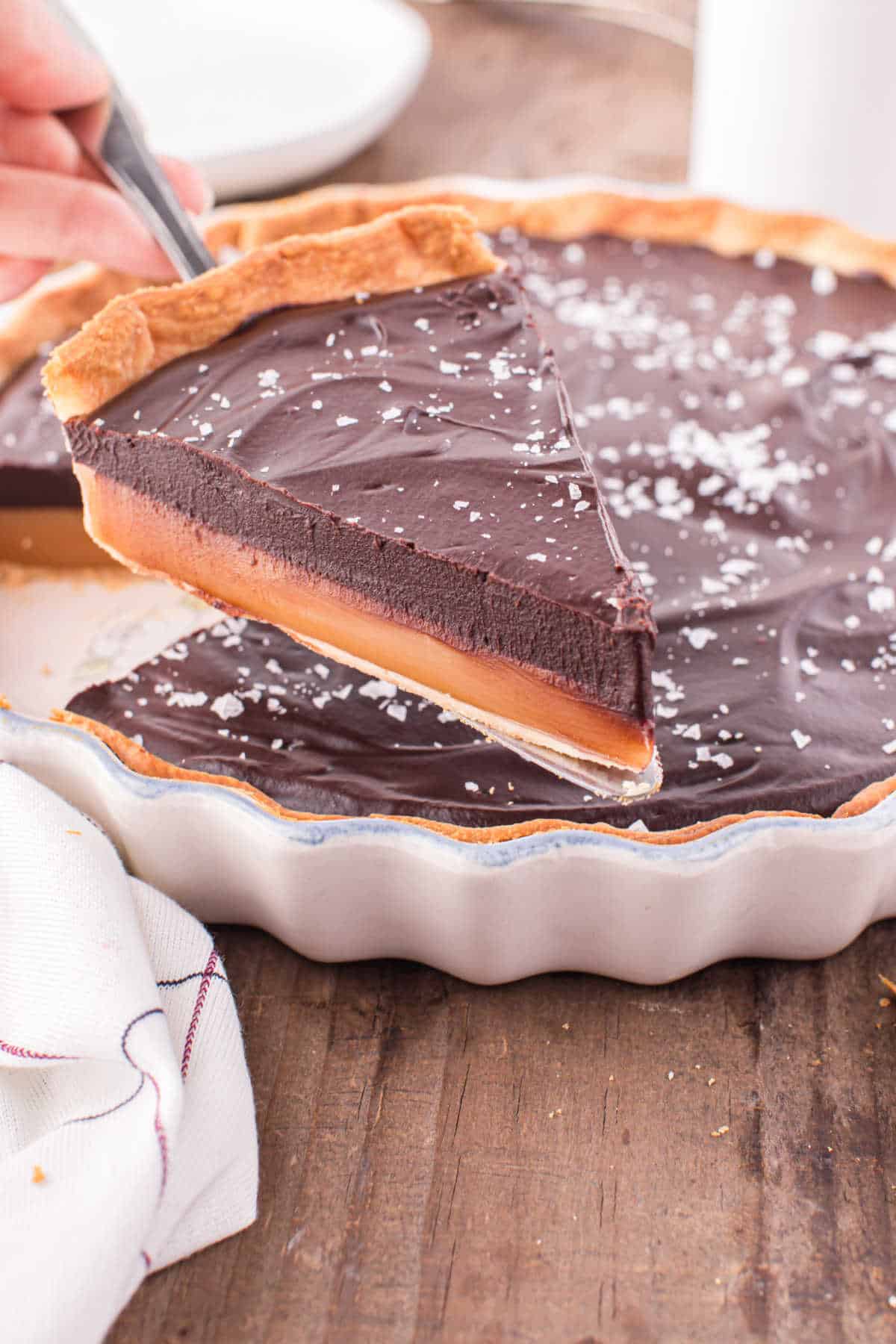 A slice of chocolate caramel tart on a spatula.