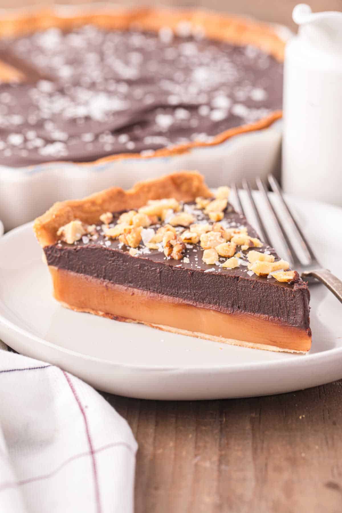 A slice of chocolate caramel tart on a plate.