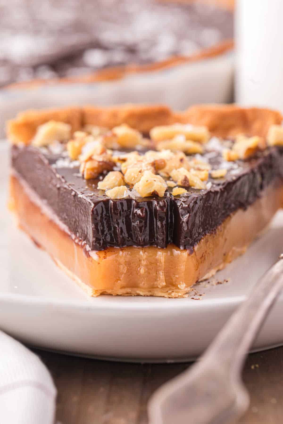 A slice of chocolate caramel tart with a bite of the end.