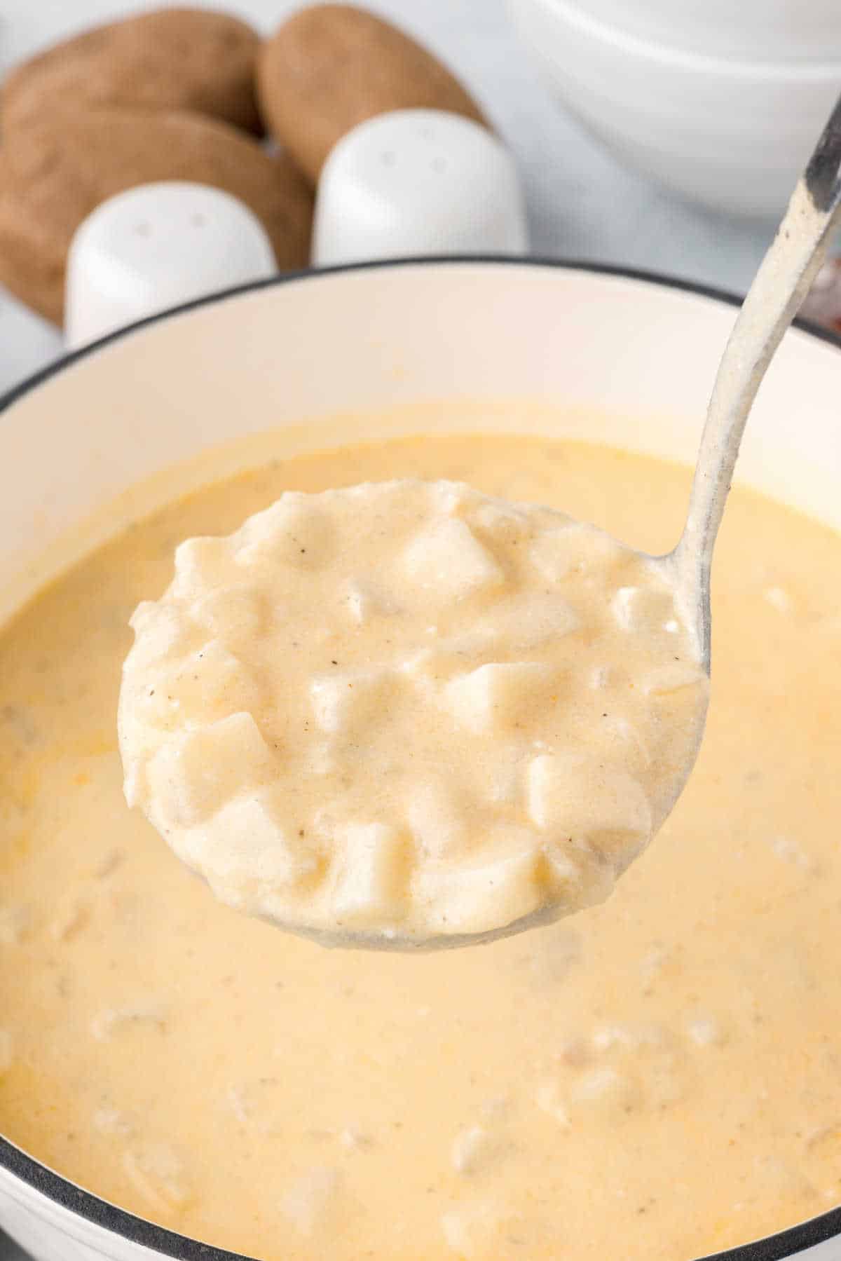 A pot of hash brown potato soup with a ladle.