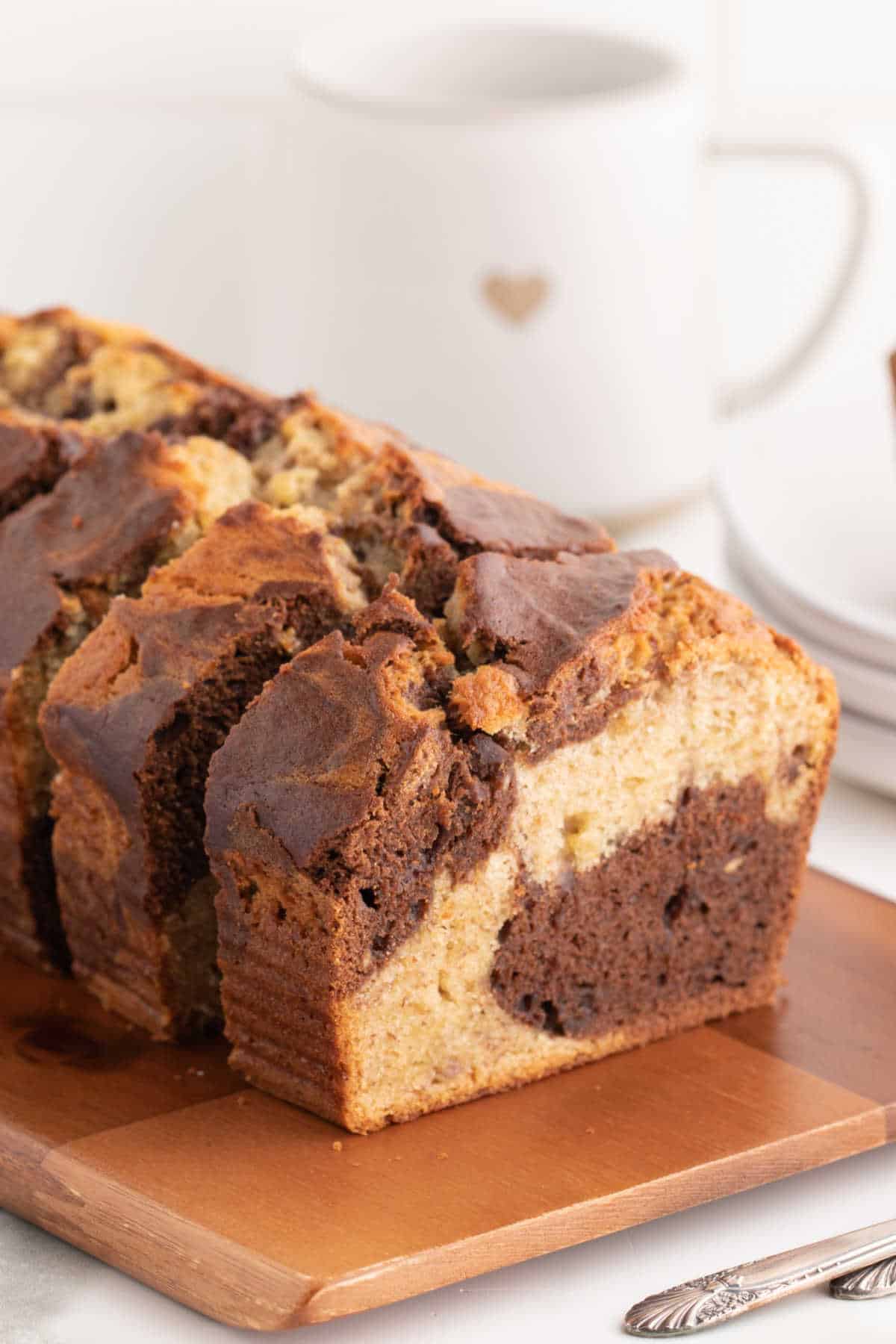 Slices of marbled banana bread on a wooden cutting board.