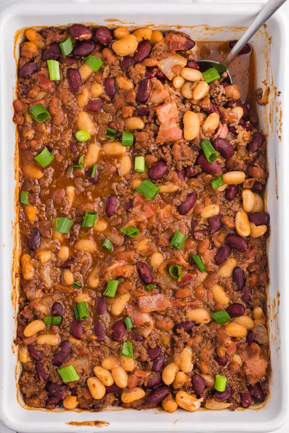 Baked bean casserole with a serving spoon.