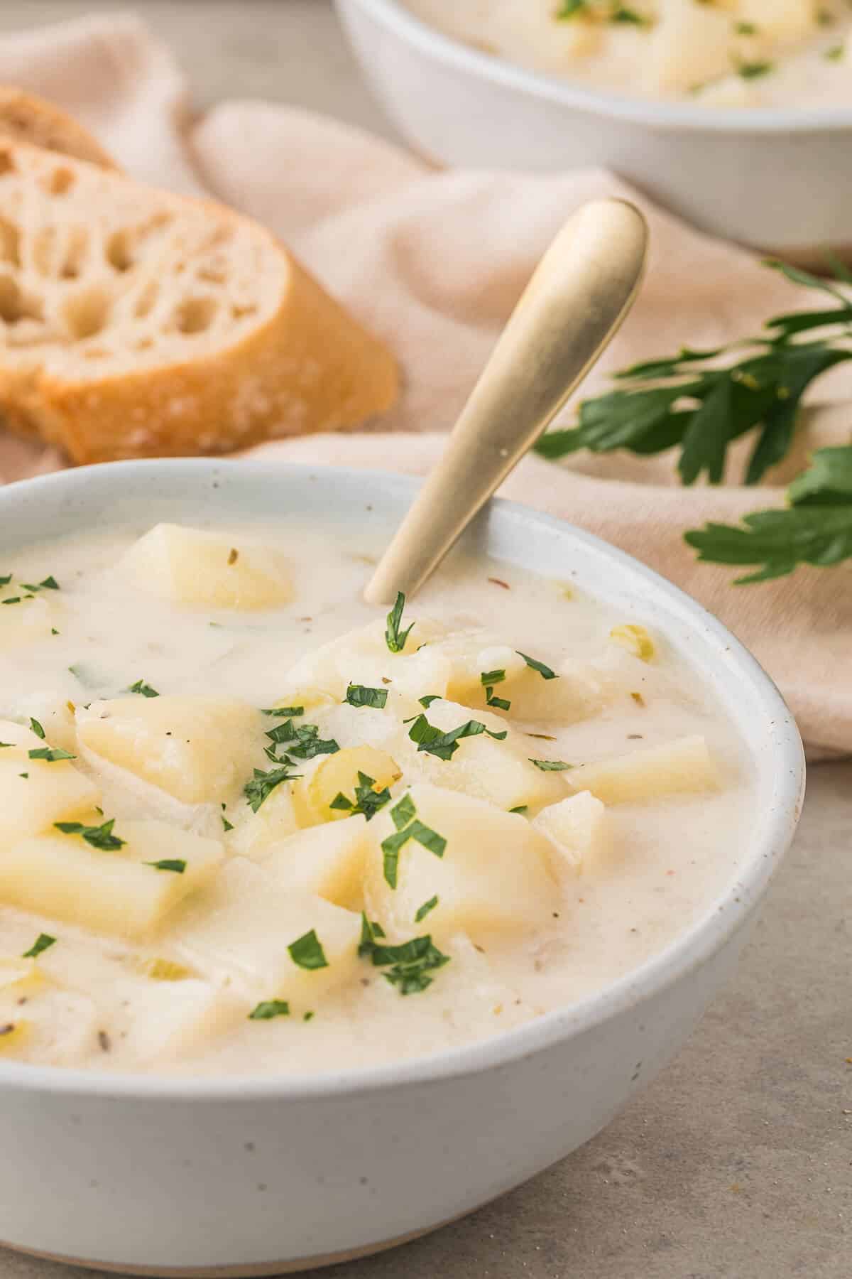 A bowl of German Potato Soup with a spoon in it.