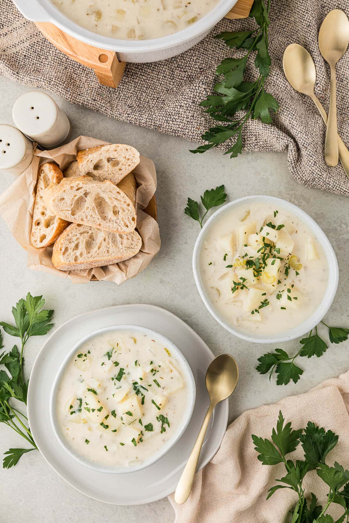 Two bowls of soup with sliced bread.