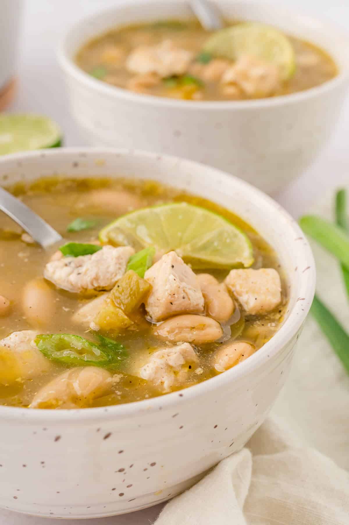 A bowl of salsa verde chicken soup with a spoon in it.