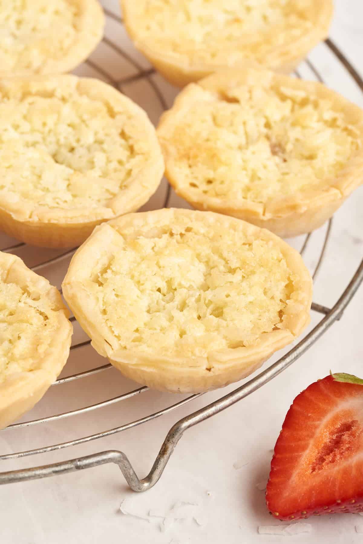 Strawberry coconut tarts on a rack.