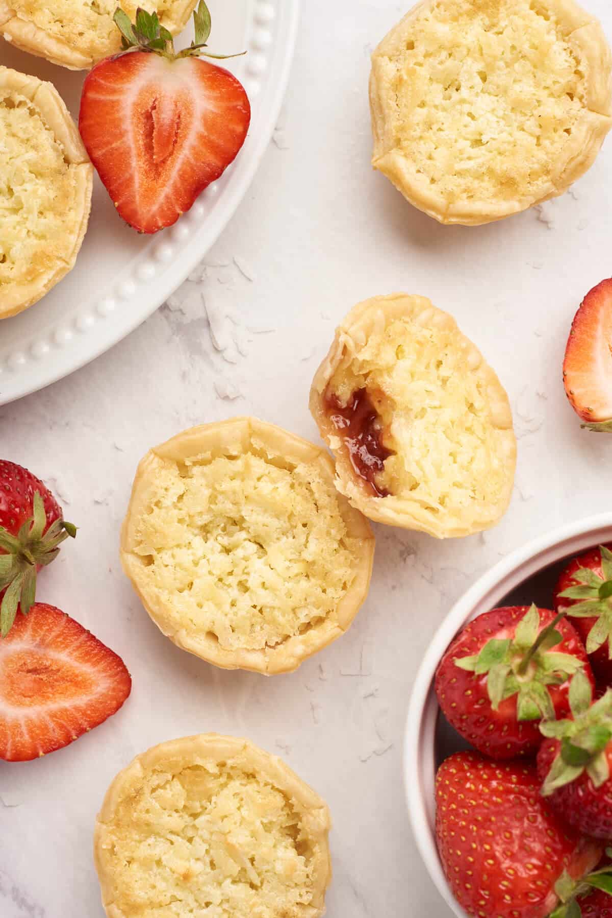 Strawberry coconut tarts on a white surface.