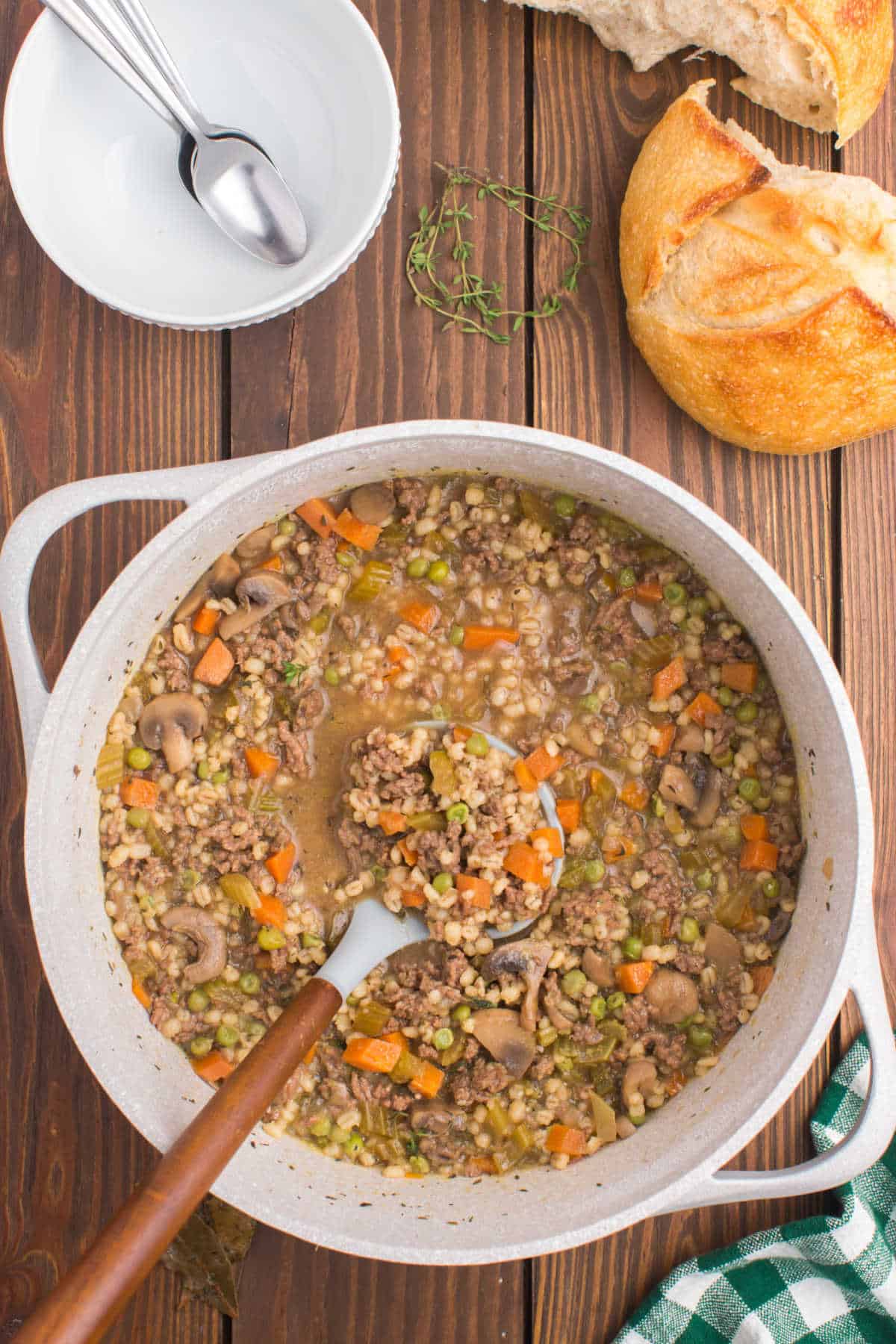 A pot of beef and barley soup with a ladle in it.