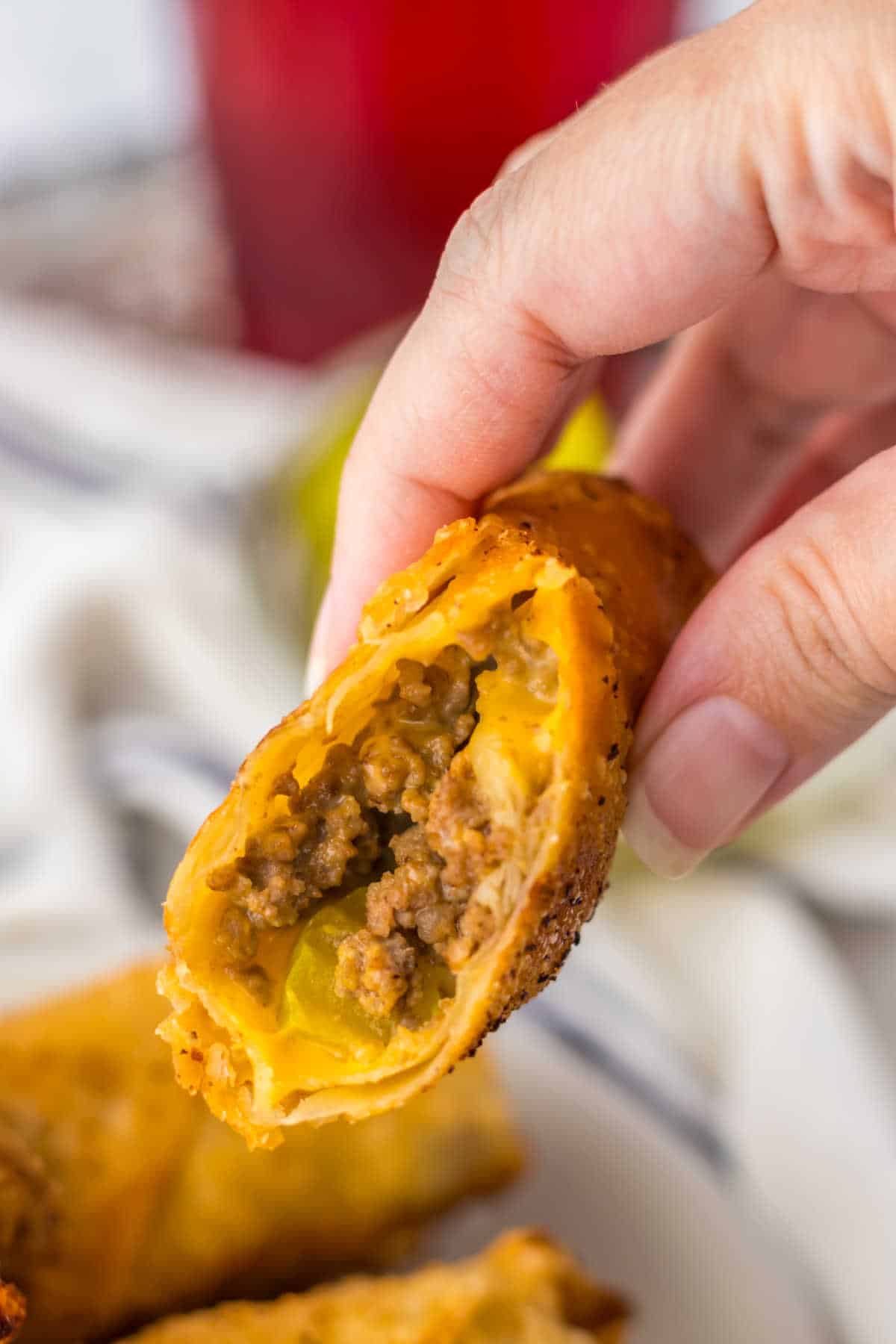 A hand holding a Big Mac Egg Roll that's been cut in half.