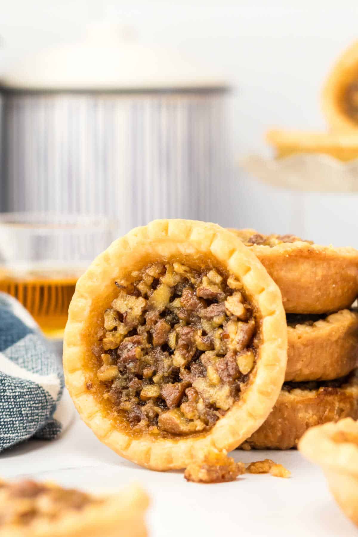 A pecan bourbon butter tart leaning against a stack of tarts.