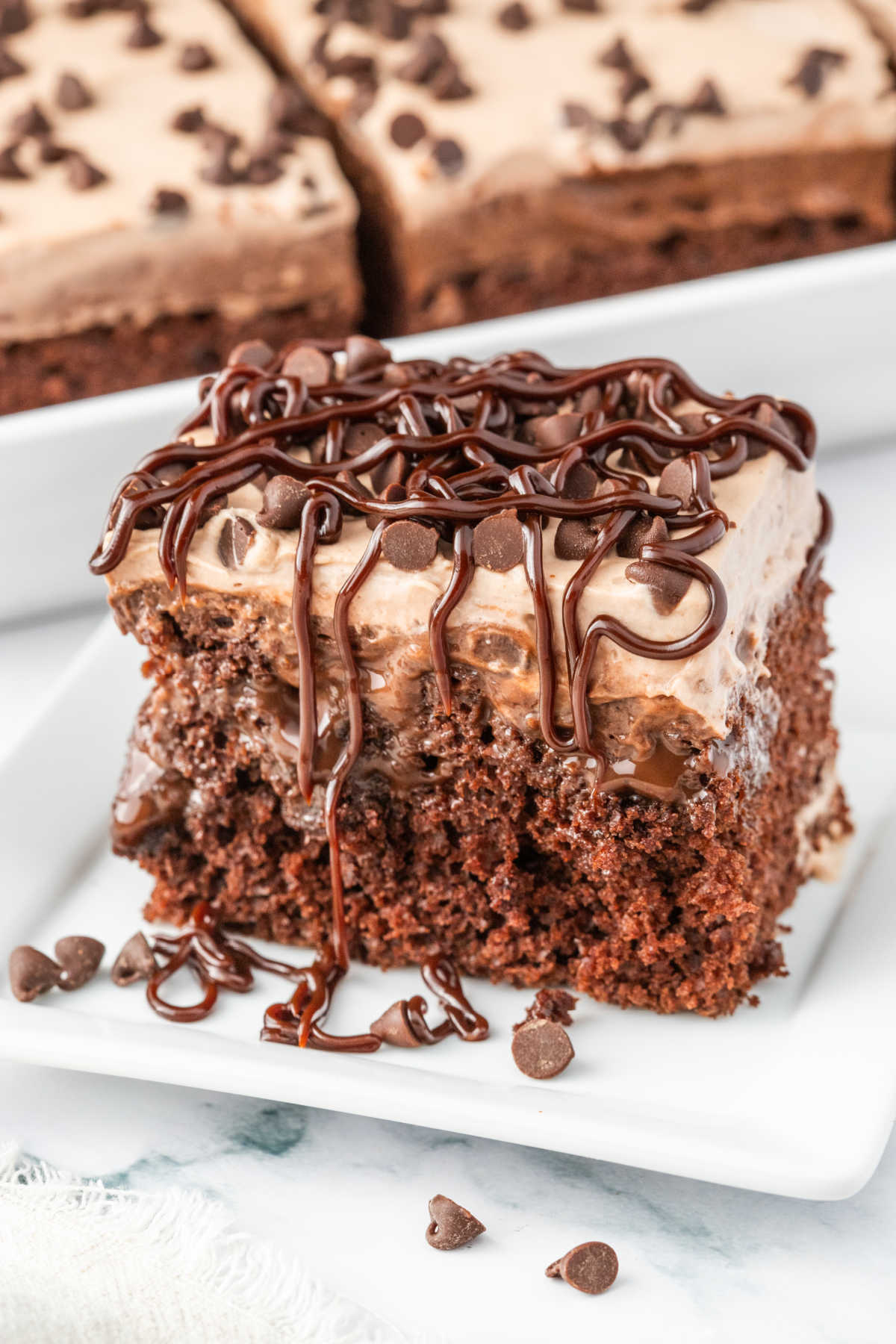 A piece of triple chocolate poke cake on a plate.