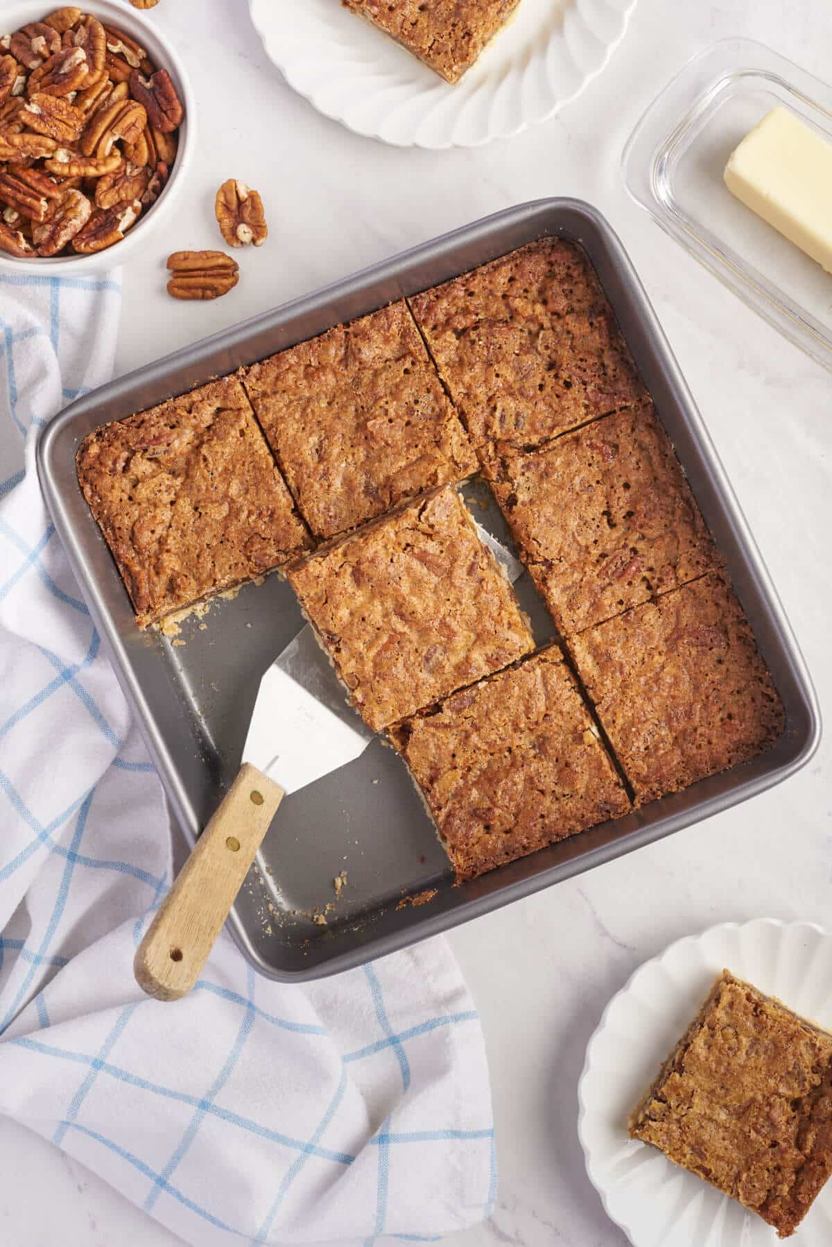 Butter tart squares in a pan with a spatula.