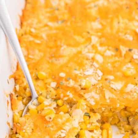 The recipe in a white casserole dish with a serving spoon..