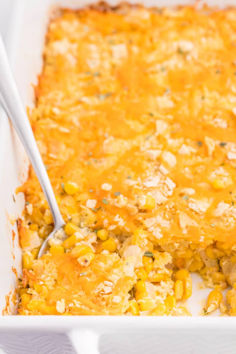 The recipe in a white casserole dish with a serving spoon..