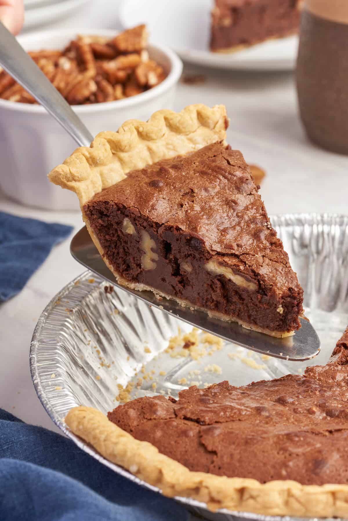 A slice of chocolate pecan pie on a spatula.