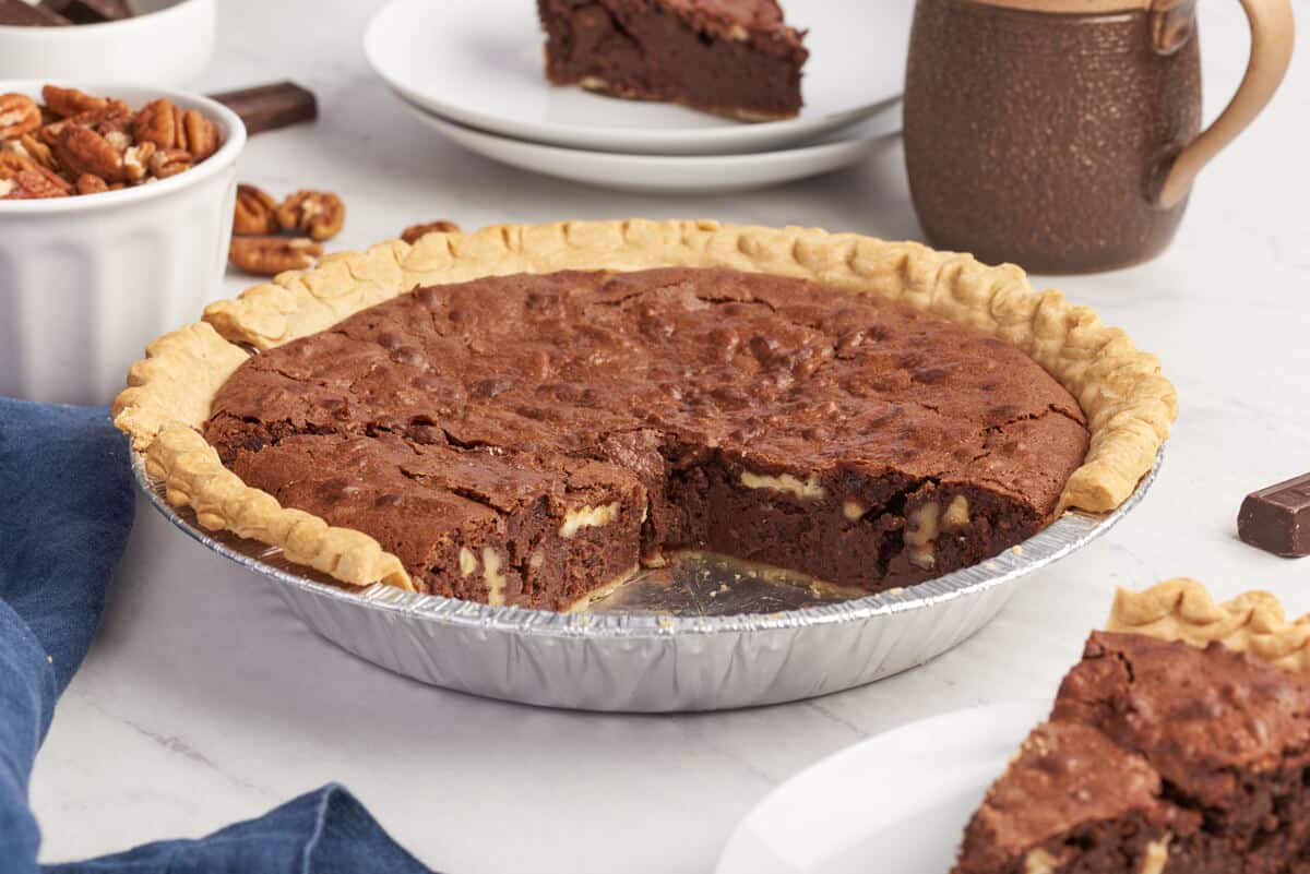 A chocolate pecan pie with slices removed.