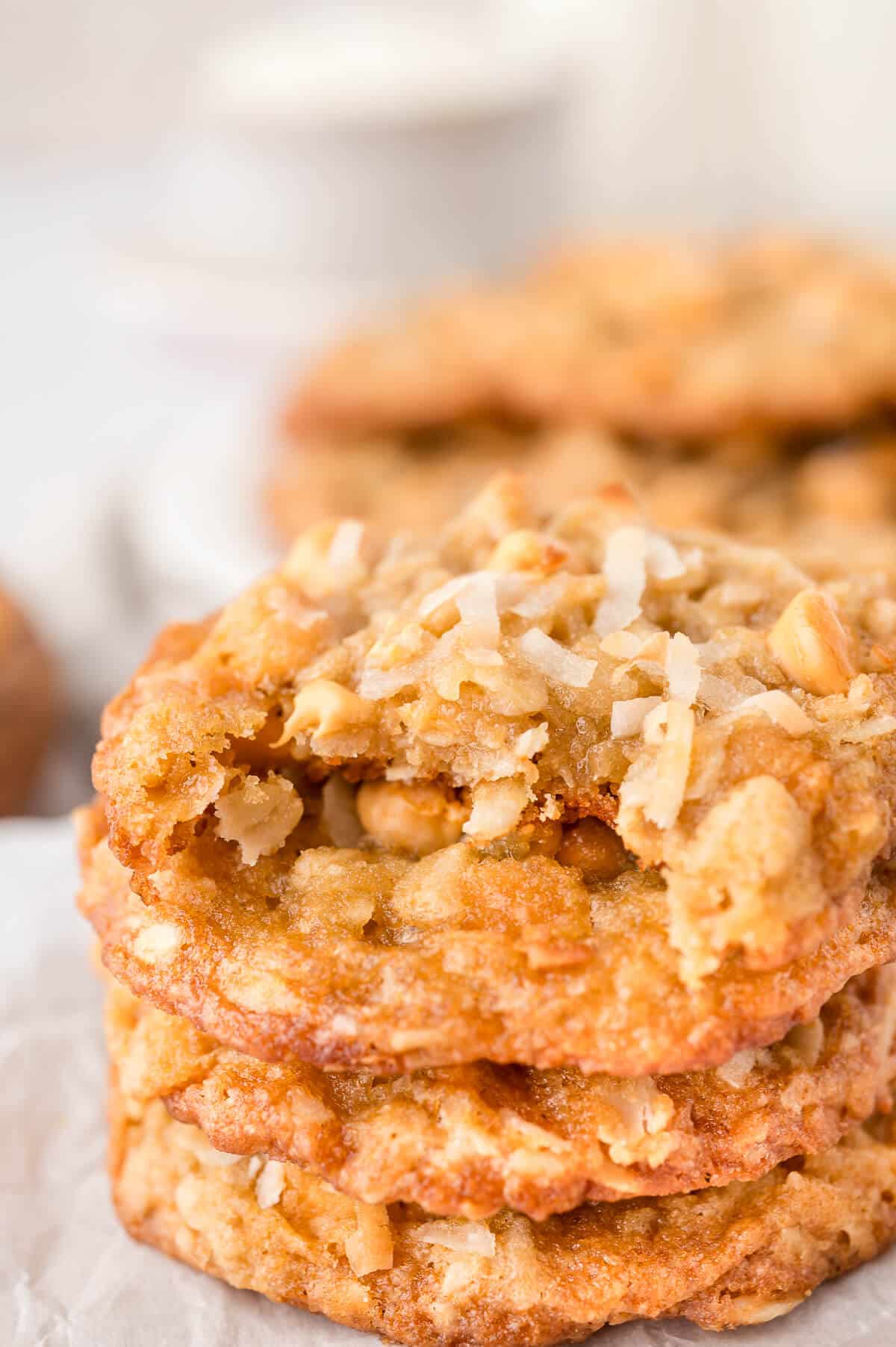 A stack of coconut butterscotch cookies with a bite out of the top cookie.