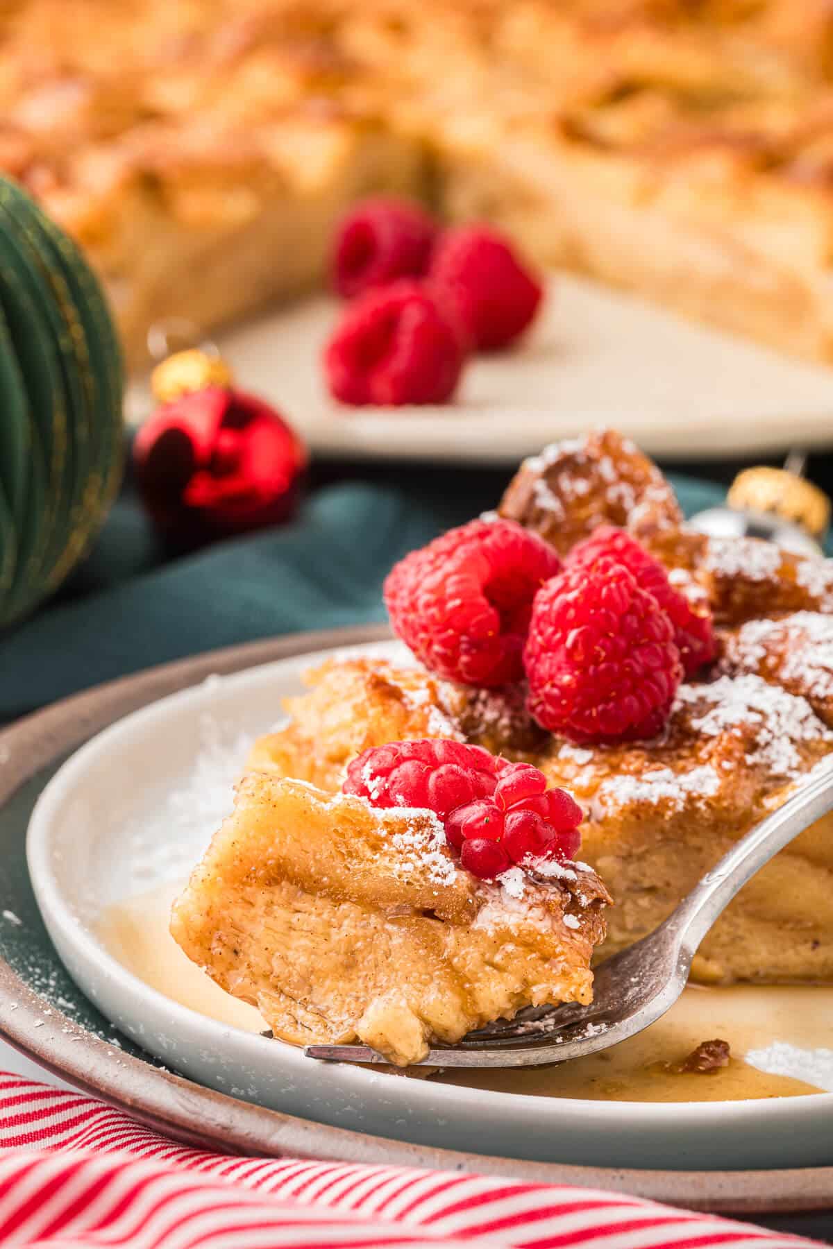 A slice of eggnog bread pudding on a plate with a fork.