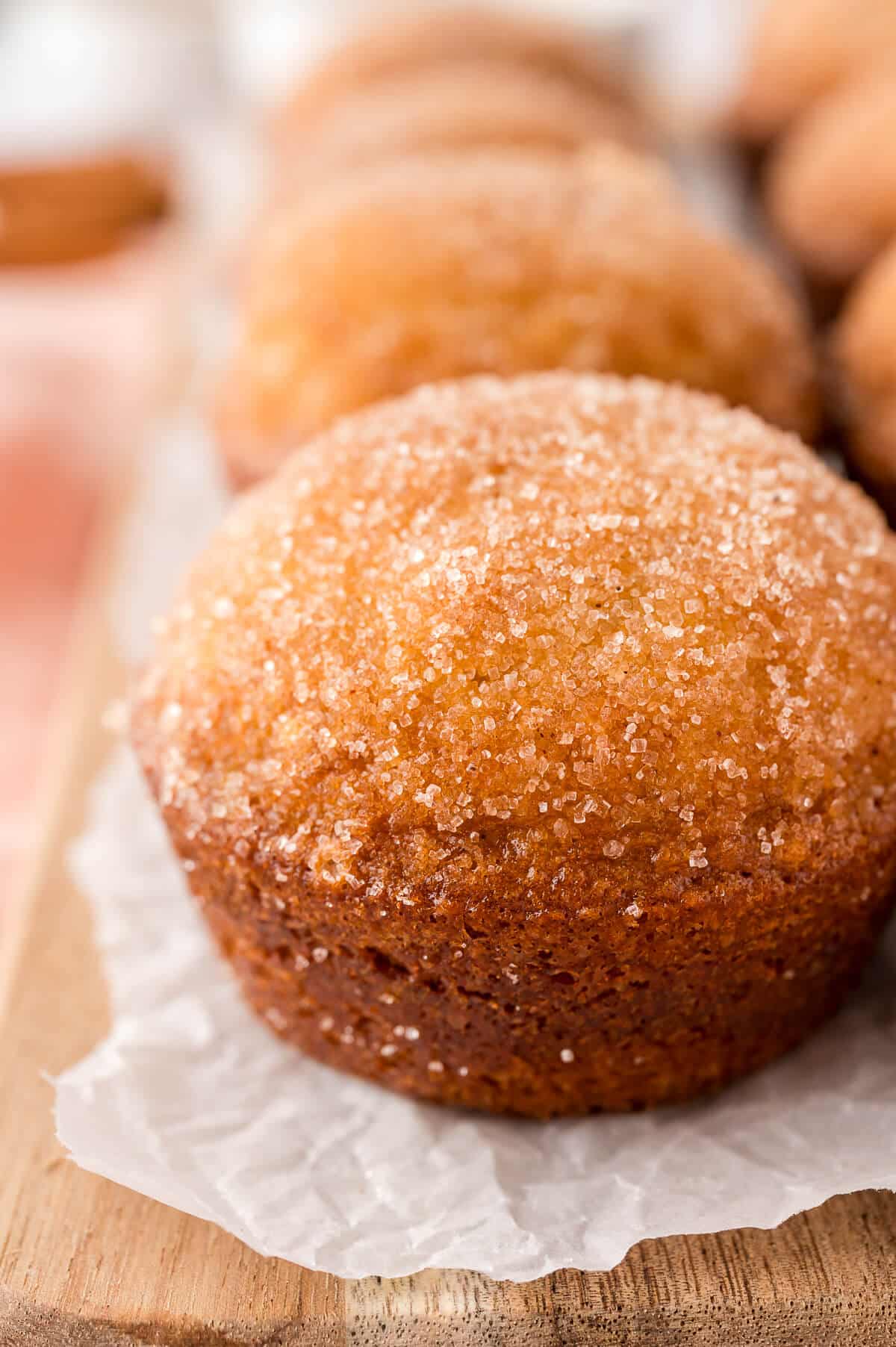 A sugar and spice muffin on a piece of parchment paper.