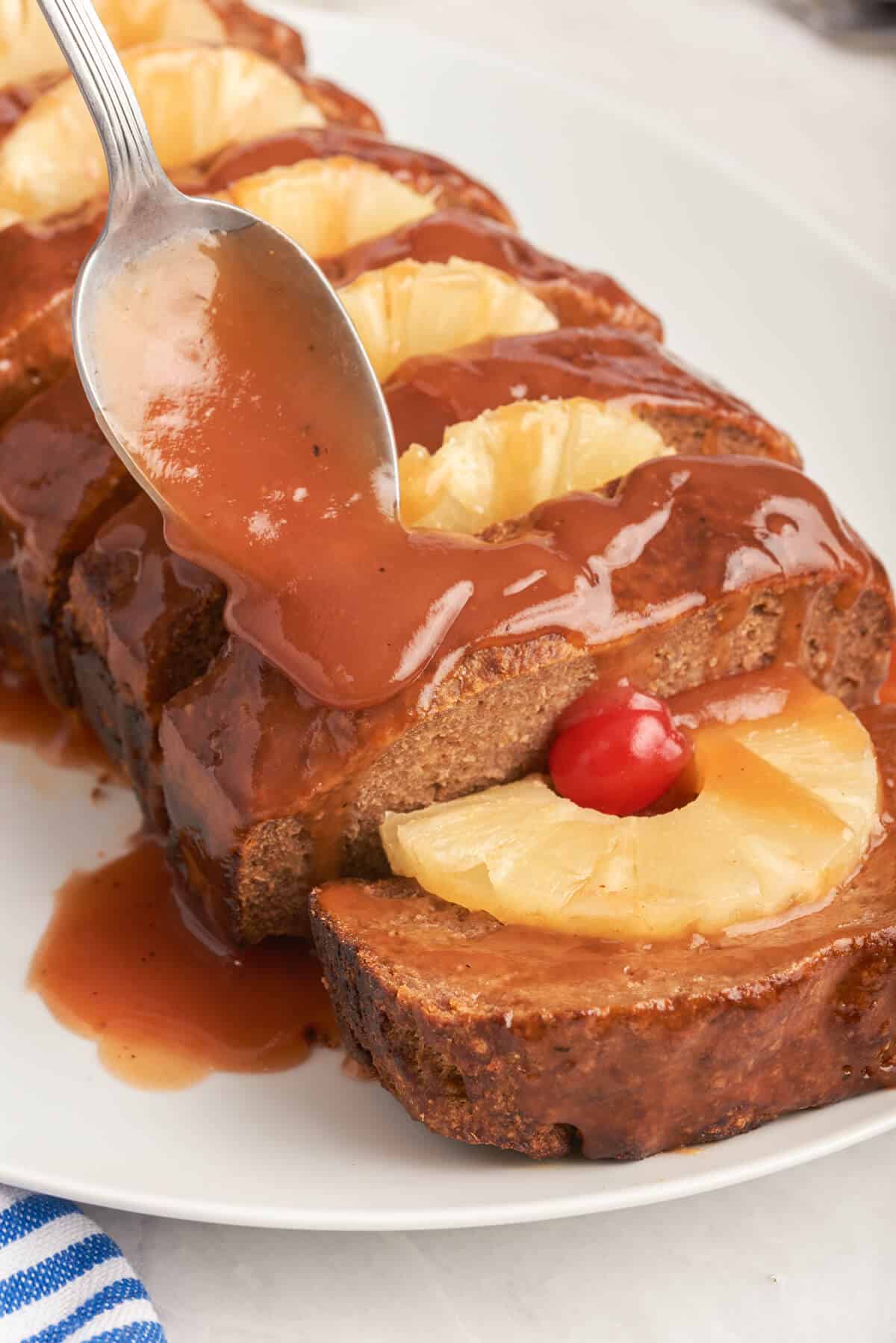 A spoon putting sauce on Caribbean meatloaf. 