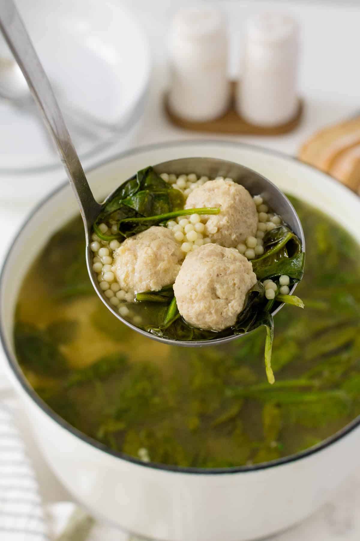 Italian meatball soup in a ladle.