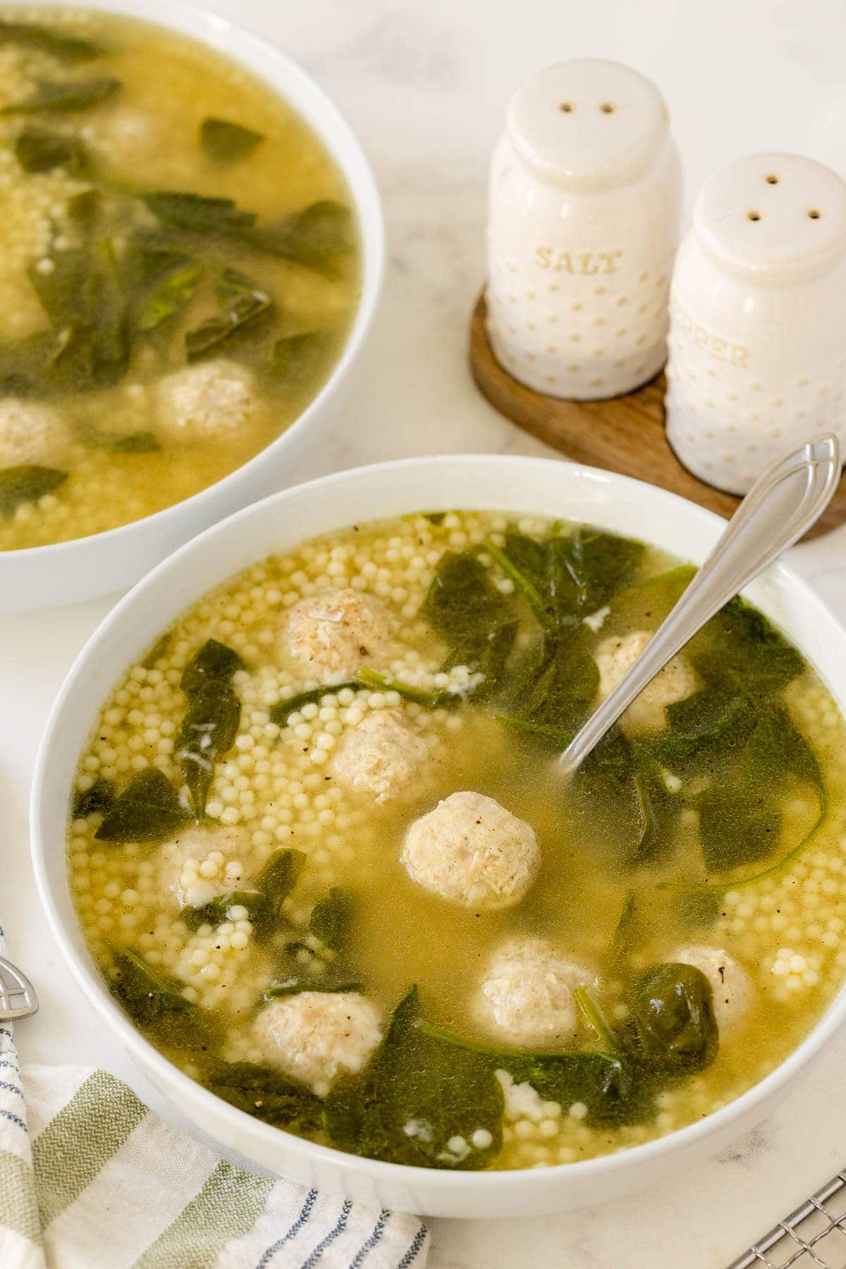 Italian meatball soup in a bowl with a spoon.