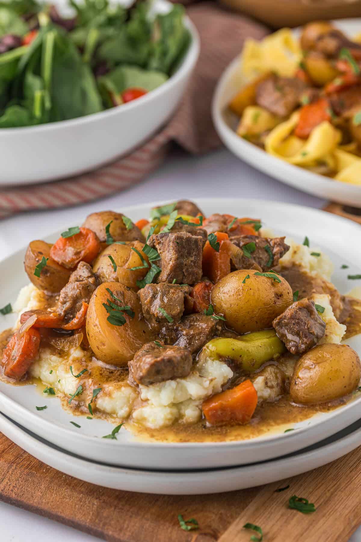 A plate of mashed potatoes topped with beef stew.