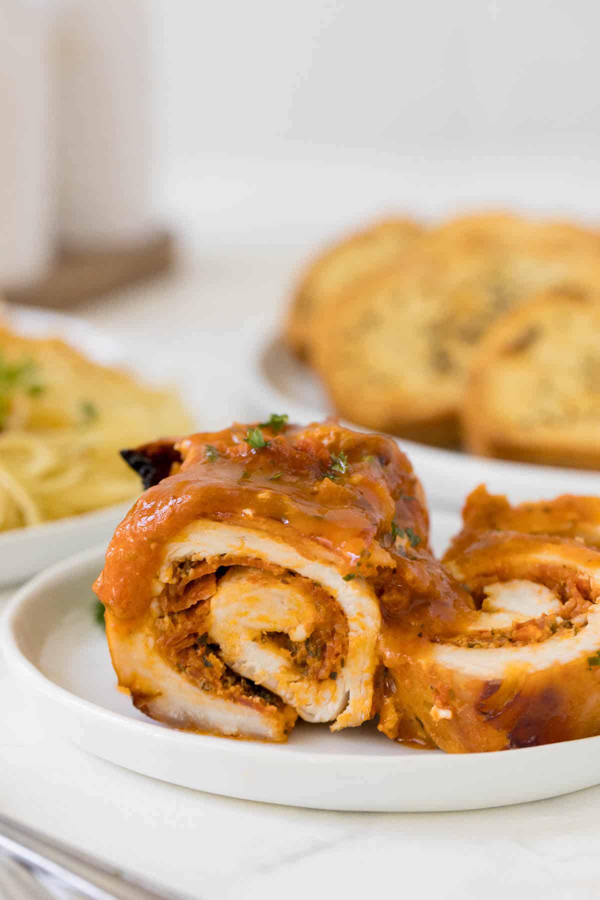 Pizza stuffed chicken cut in half on a plate.