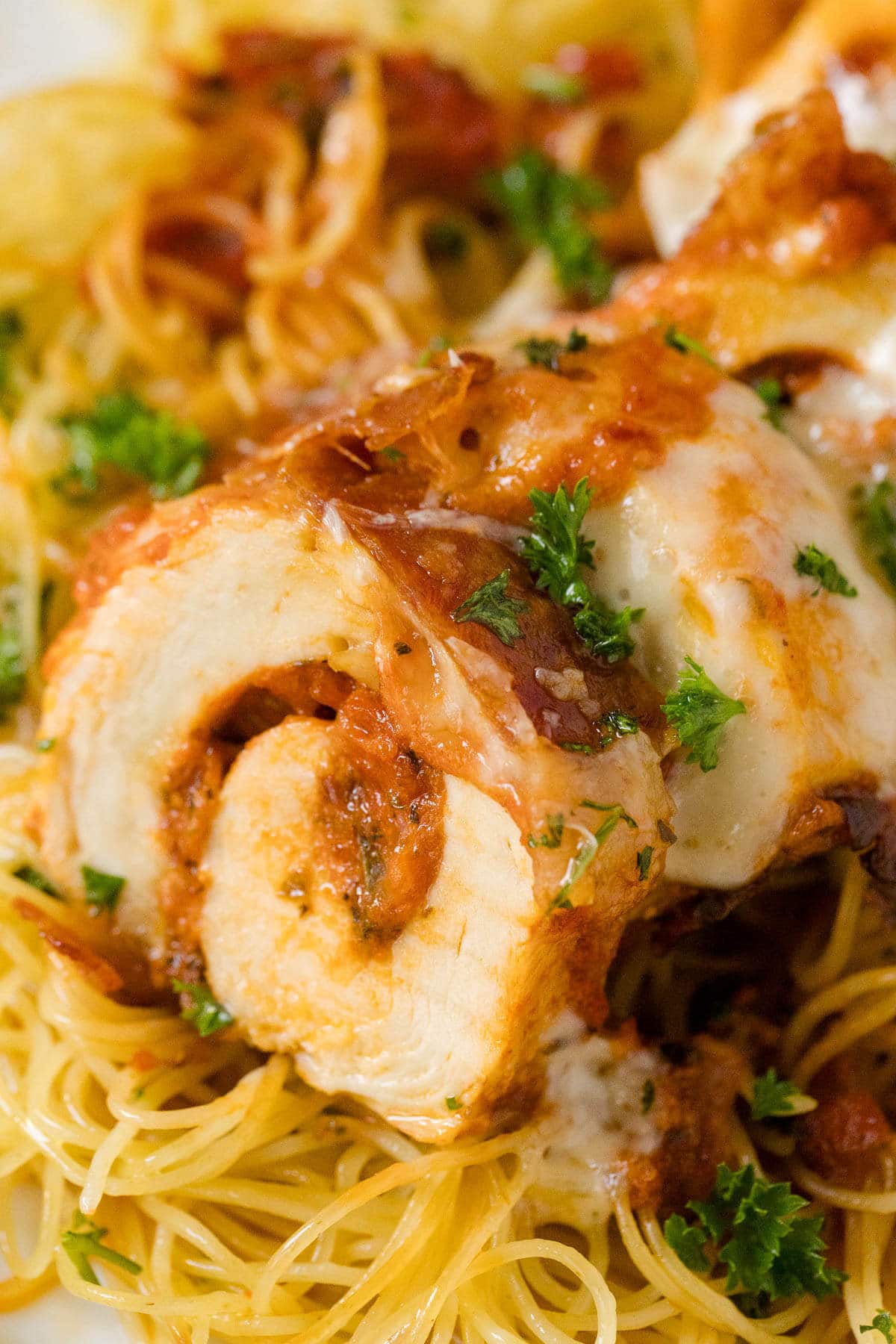 Pieces of pizza stuffed chicken served over spaghetti.