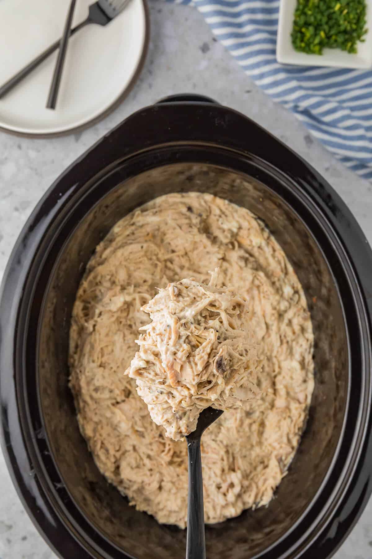 Slow cooker cream cheese chicken in a crockpot with a serving spoon.