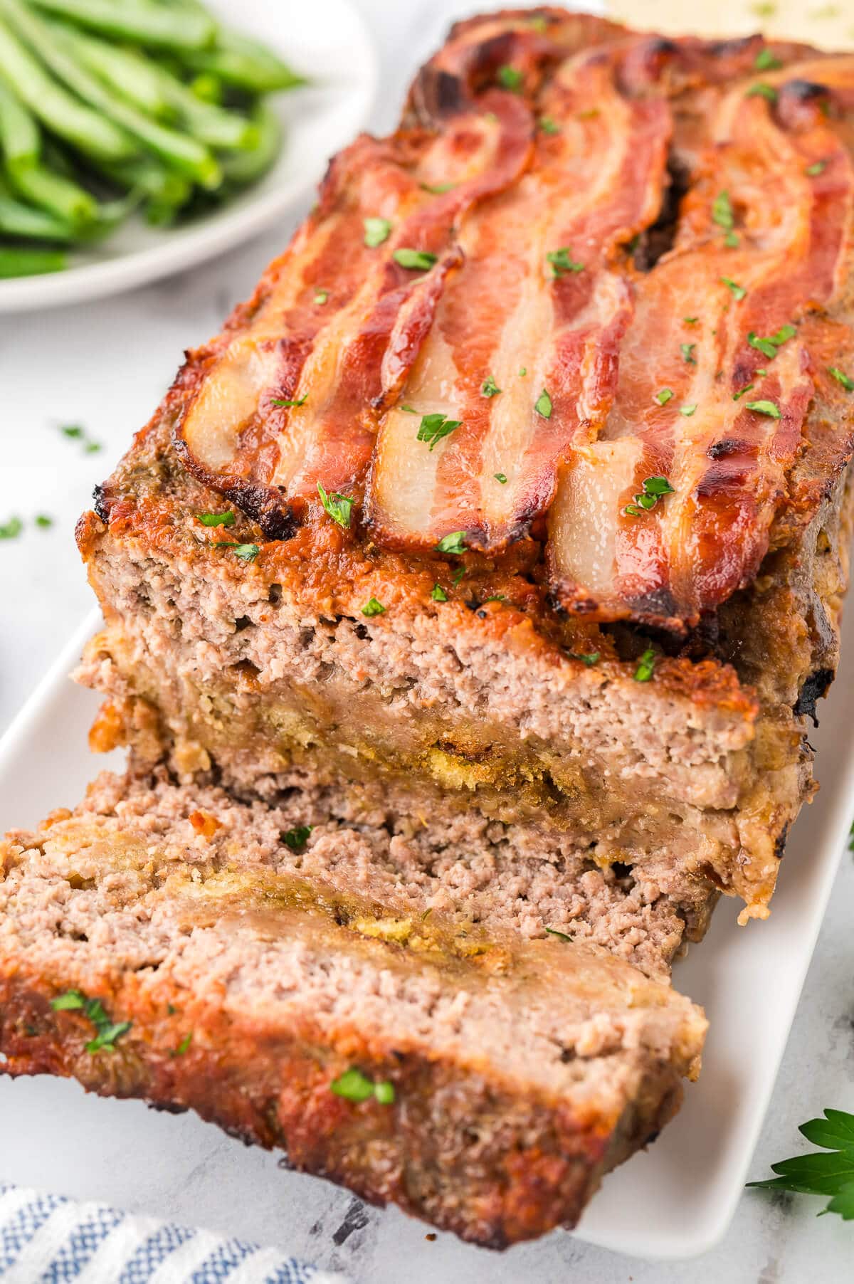 Sunday meatloaf on a platter with slices cut.