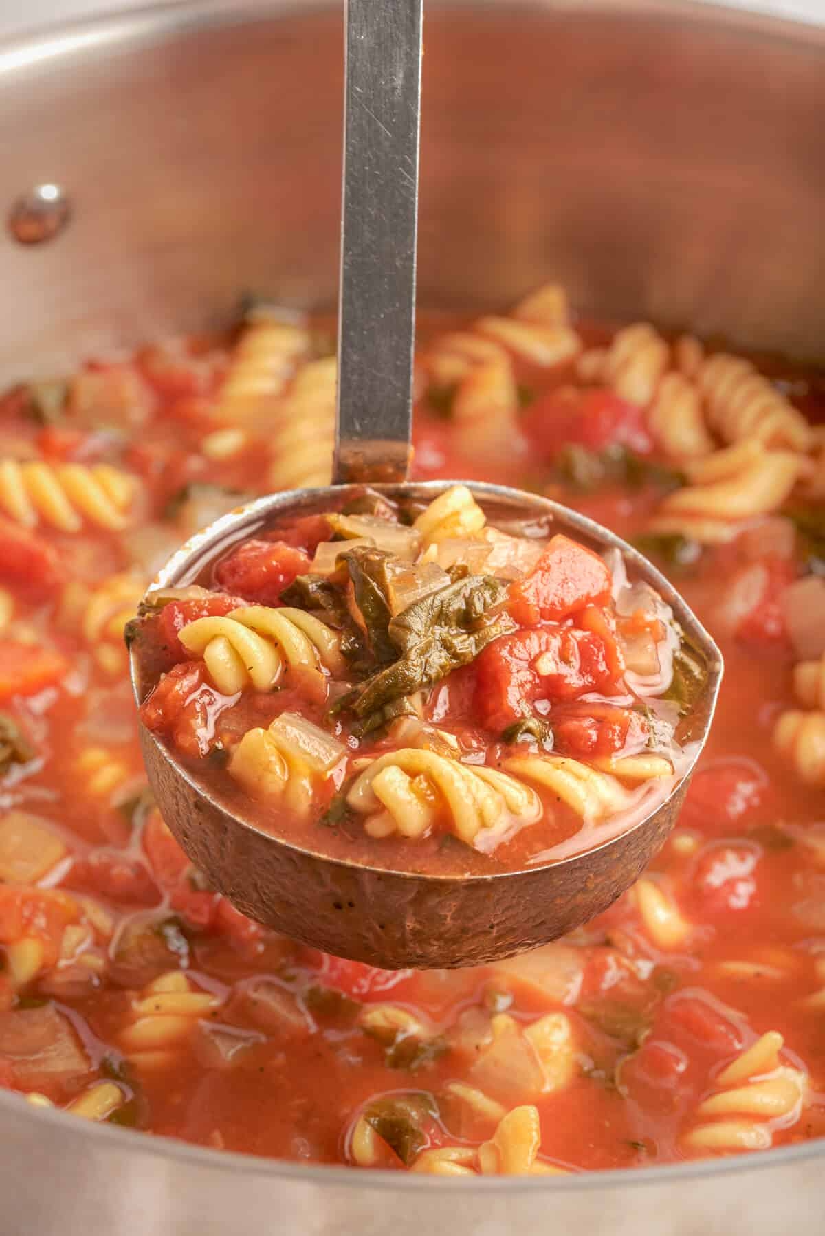 A soup ladle of tomato florentine soup.