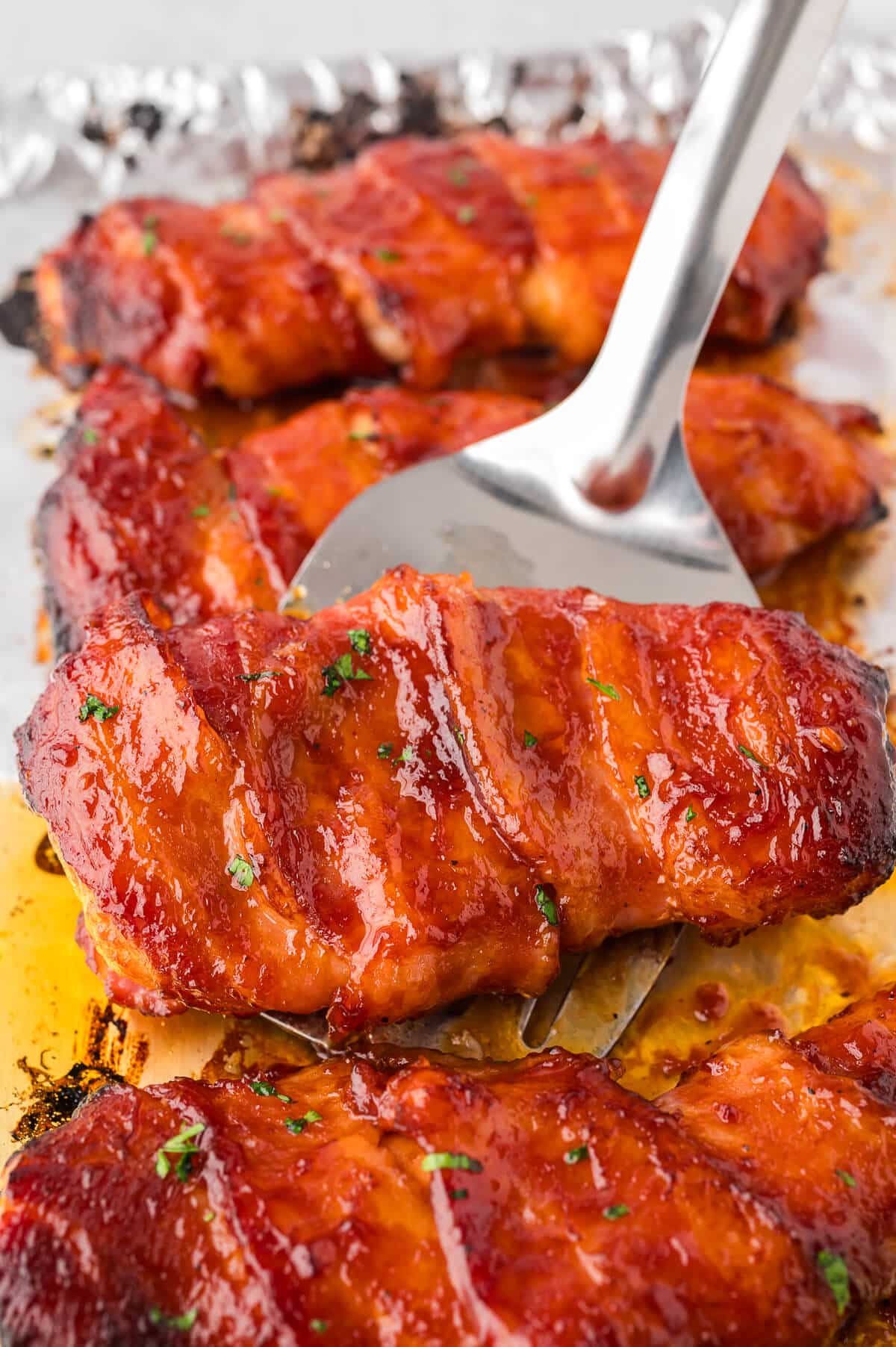 A bacon wrapped chicken on a spatula.