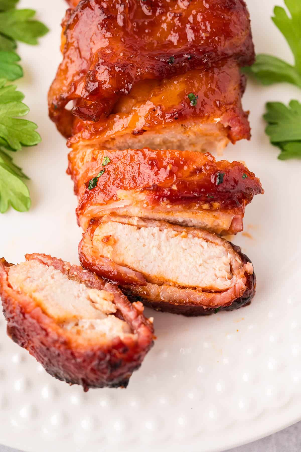 Sliced bacon wrapped chicken on a plate.