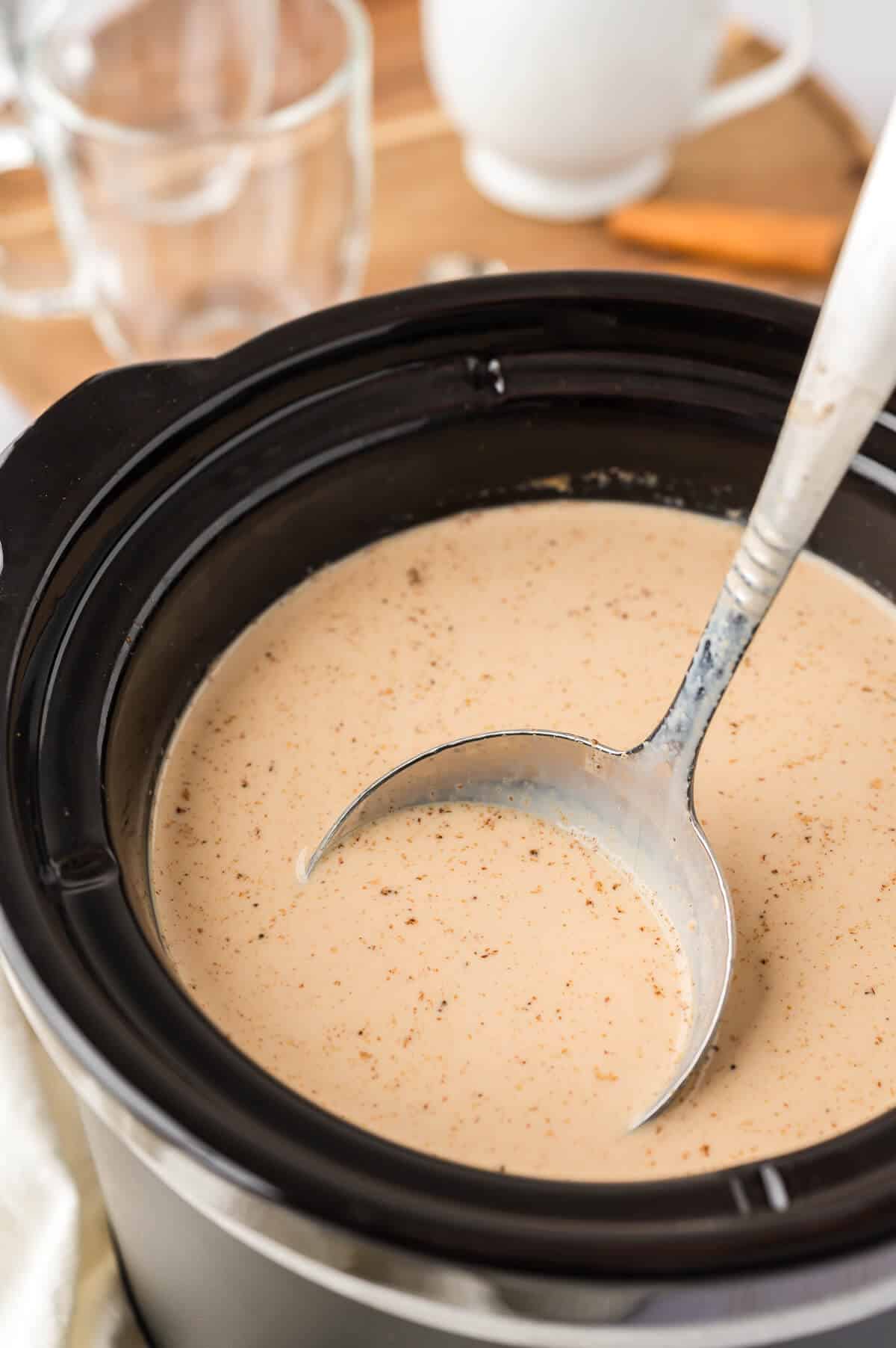 Chai latte in a slow cooker with a ladle.