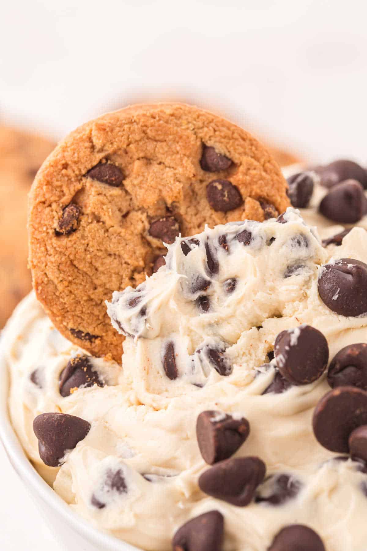 A chocolate chip cookie in cookie dough dip.