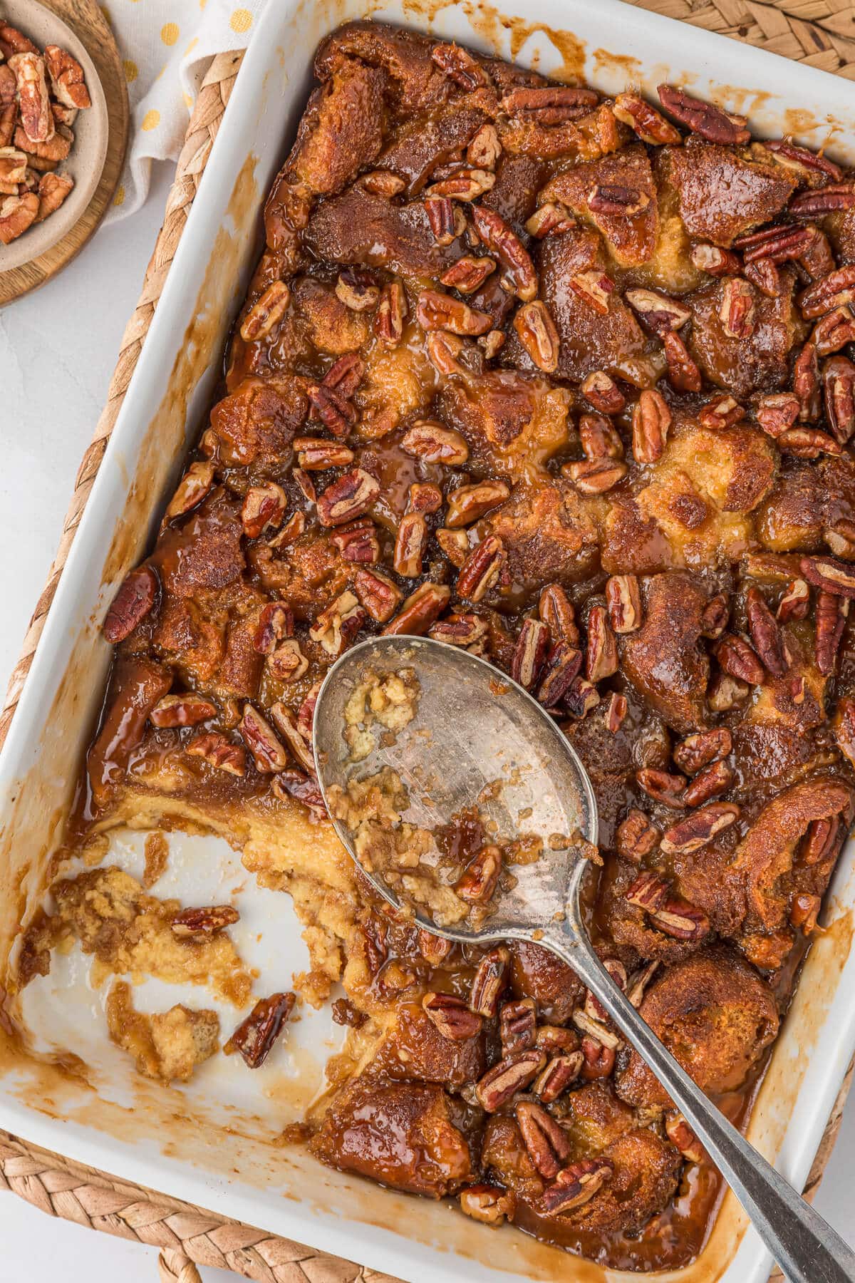 Caramel pecan breakfast casserole in a white pan with a serving spoon.