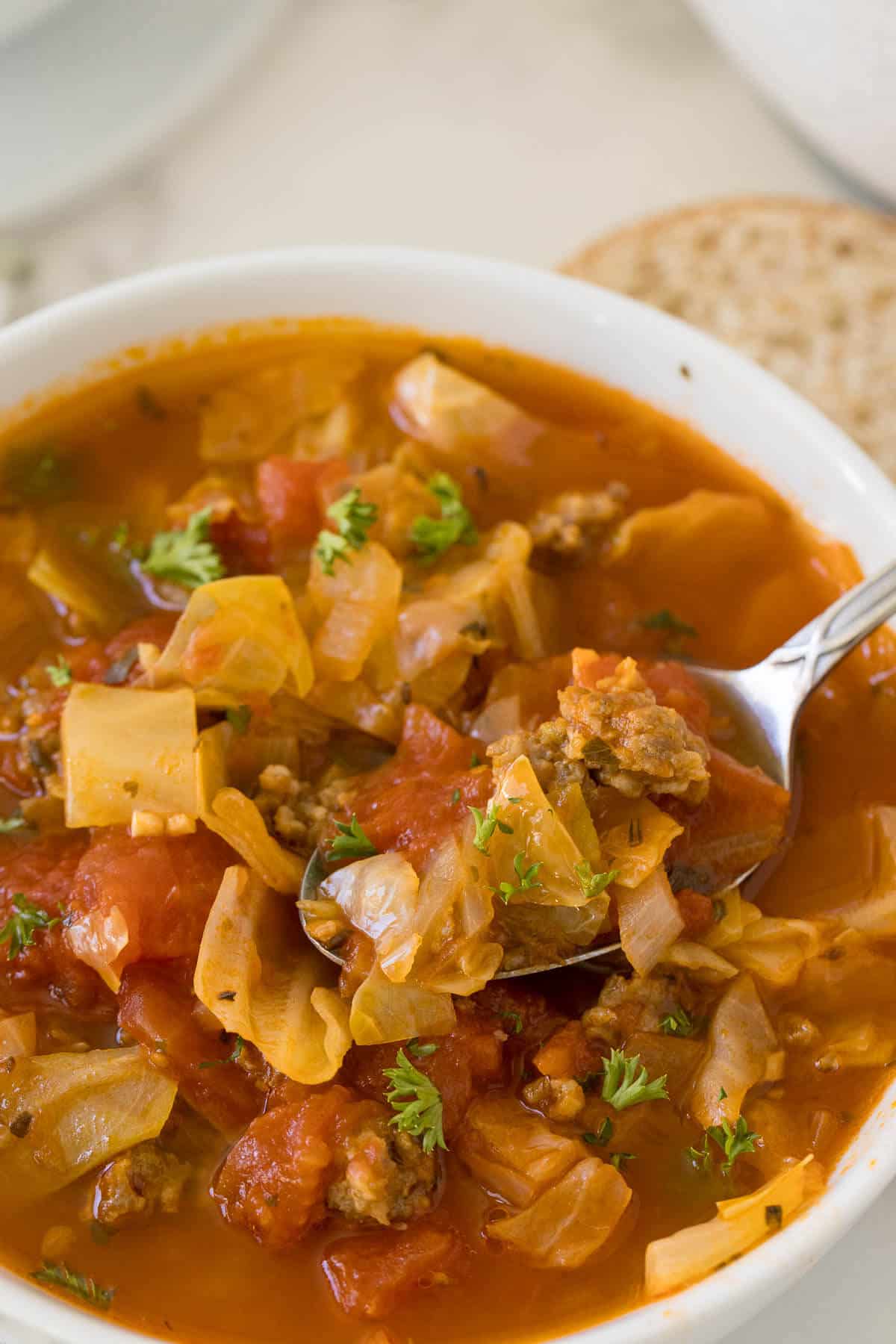 Sausage and cabbage soup in a bowl with a spoon.