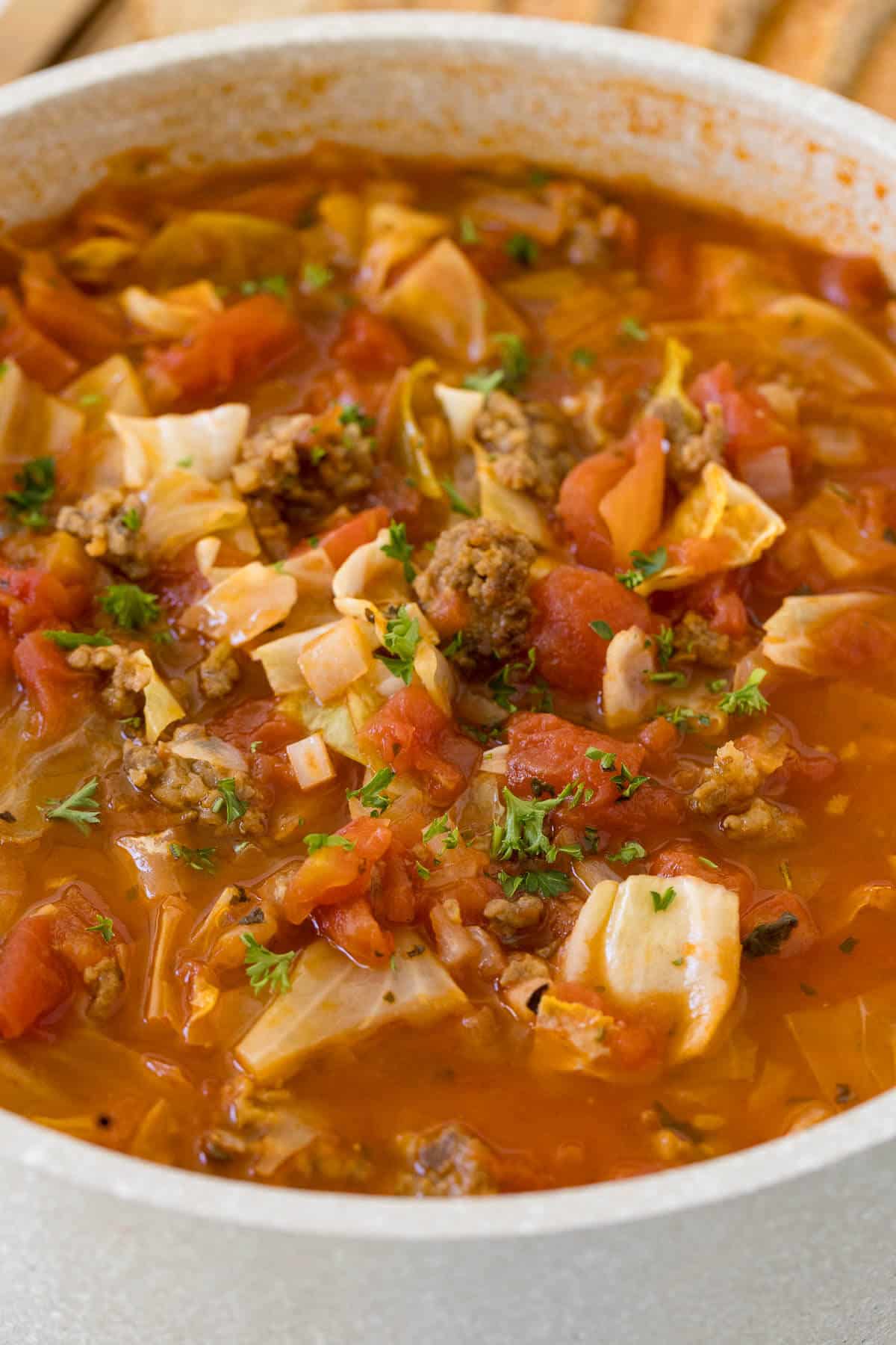 Sausage and Cabbage Soup in a white pot.